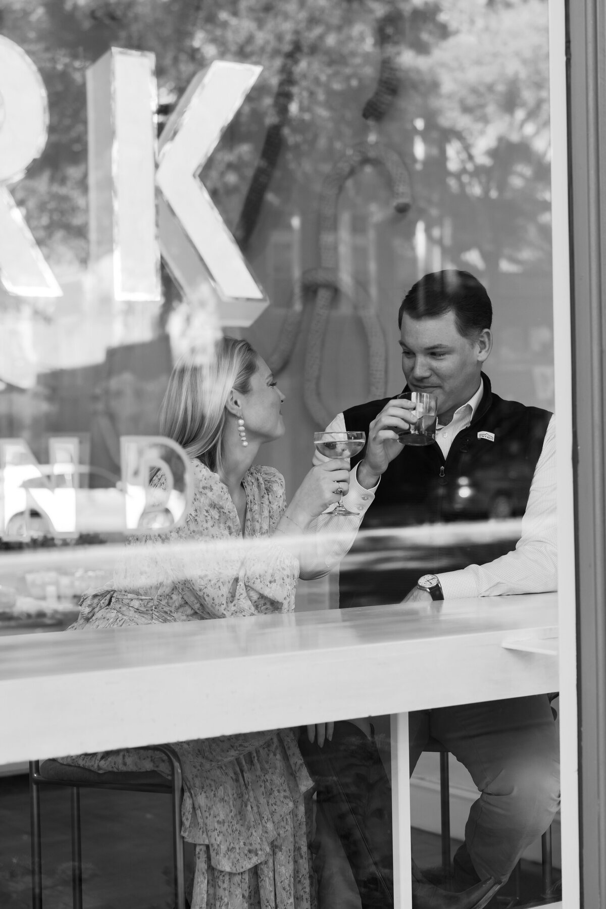 Quirk Hotel Bar Engagement Photos | black and white image through the window of a couple having a cocktail at the Quirk Hotel in Richmond VA