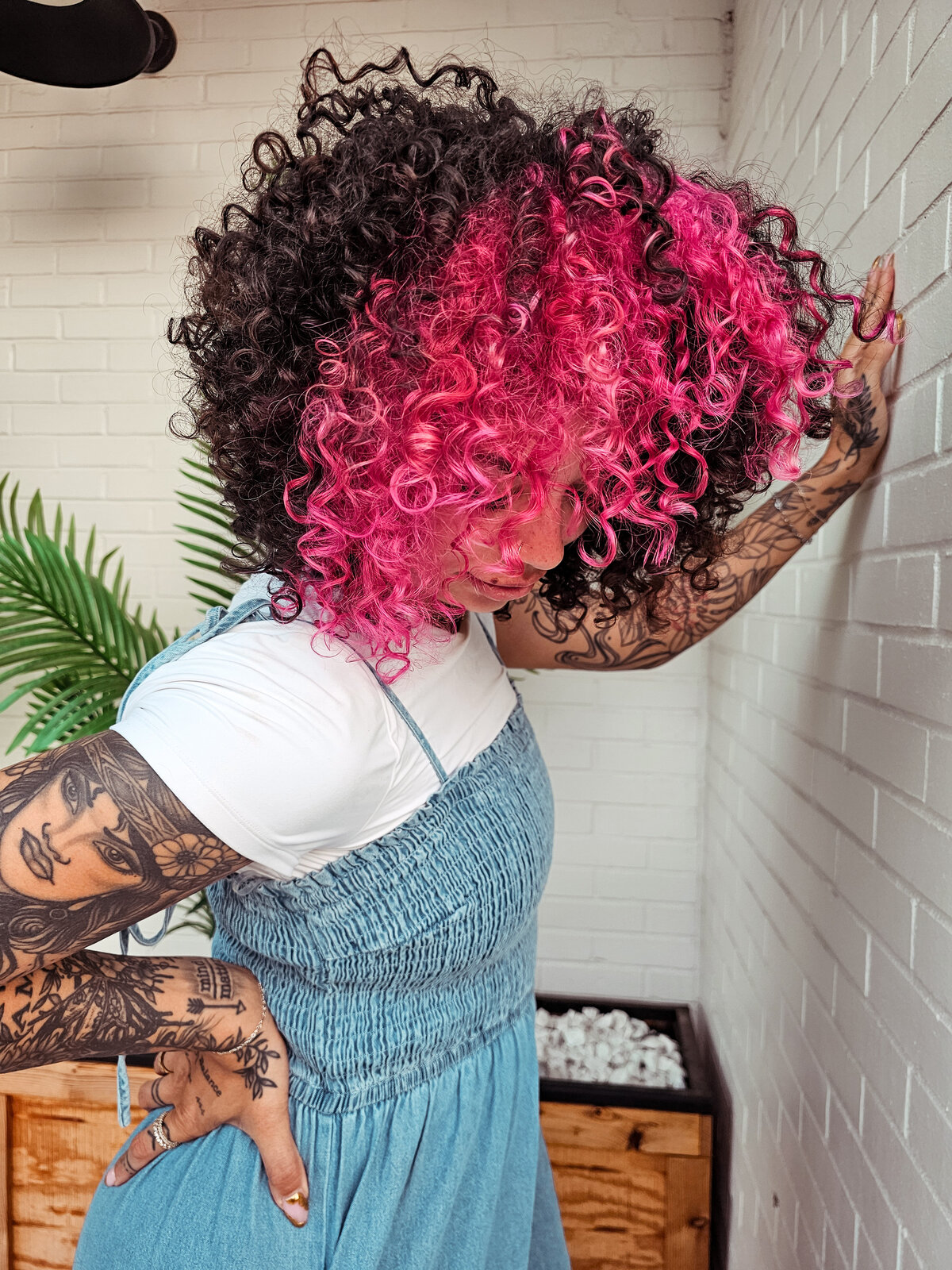 A vivid neon pink section on big, curly hair from a client of Moxie by KC