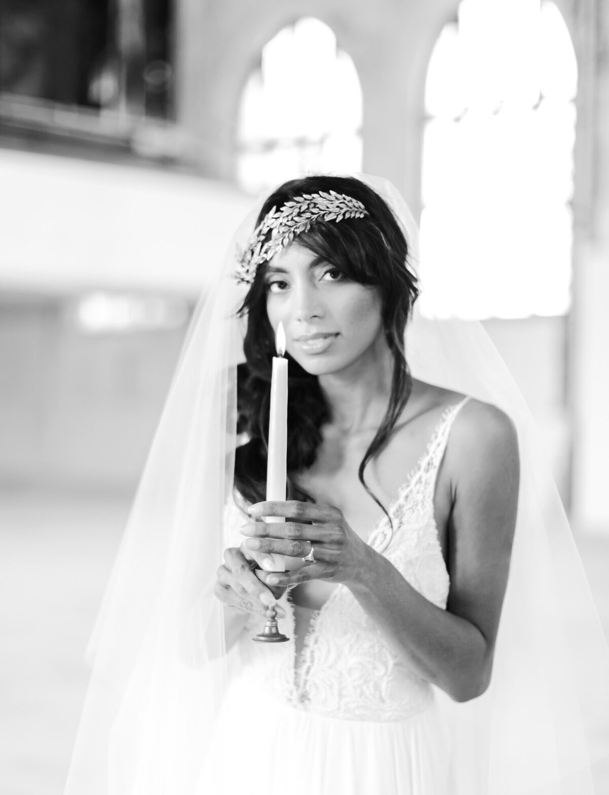 bride gazes at camera with taper candle in abandoned cathedral wedding, ruins venue in Italy