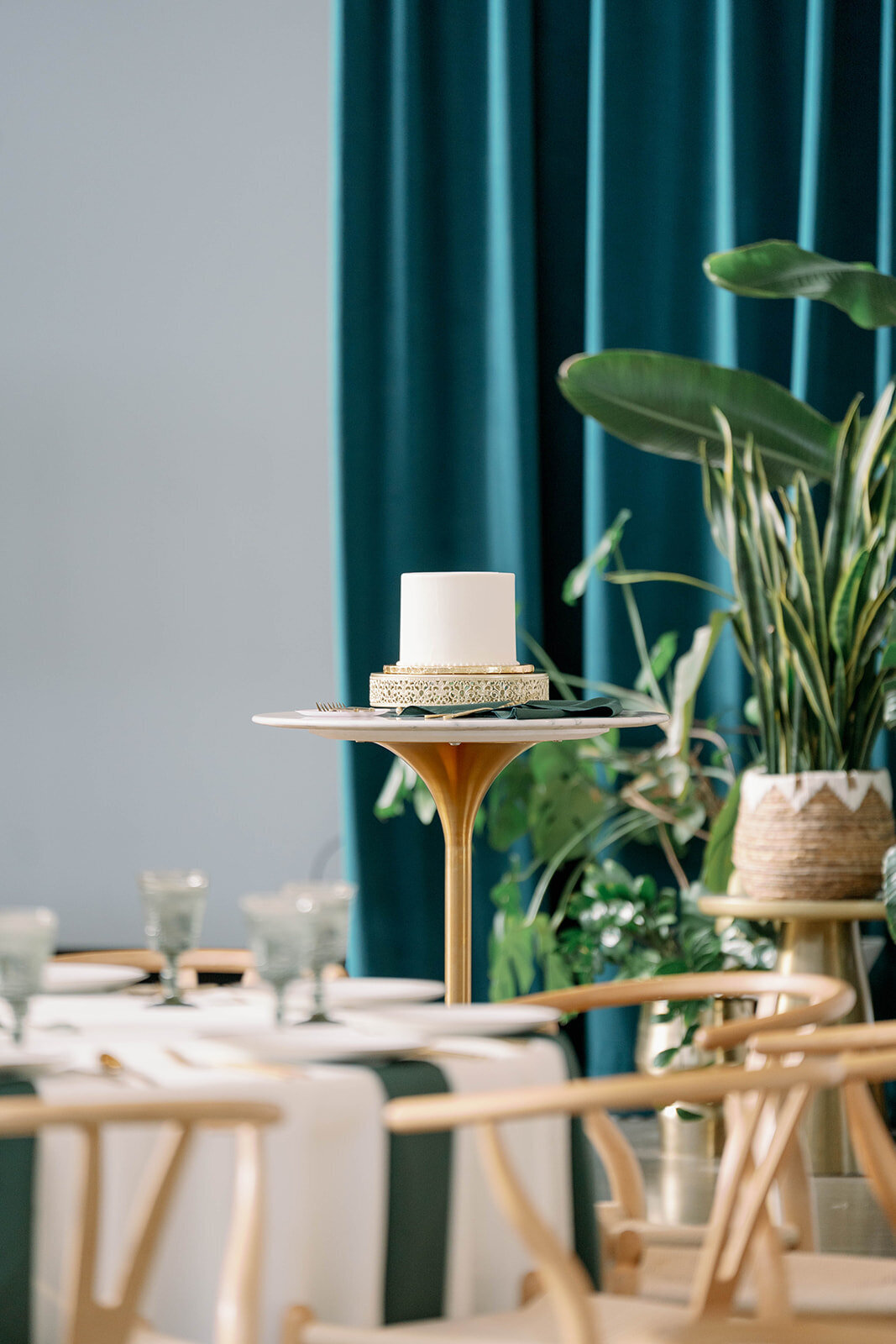 Close-up of the wedding cake surrounded by plants and styled décor during a Leona Road reception in Grand Rapids, Michigan.