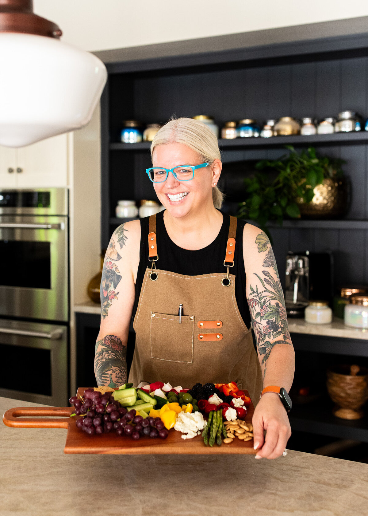 Vegan chef smiles at camera while showcasing her veggie tray during a session with a Portland branding photographer. 
