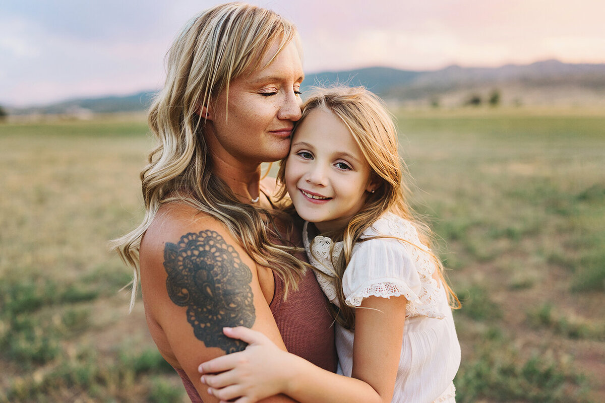 Mom hugging daughter while little girl smiles
