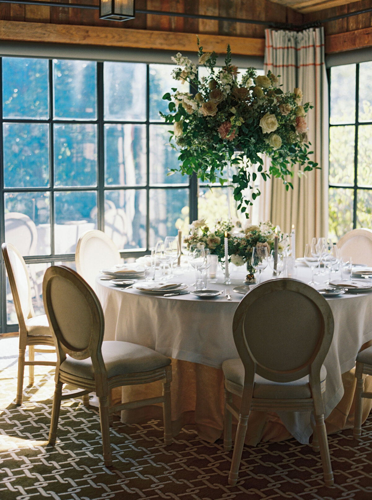 Elegant and timeless floral design for wedding reception tables. Wedding dinner at The Barn on Blackberry Farm. Garden inspired growing floral in colors of cream, white, blush, and green. Whimsical floral design for low centerpieces and elevated arrangements at fall wedding reception. Romantic candlelight and timeless floral design for elegant tablescapes. Destination wedding at Blackberry Farm. Design by Rosemary & Finch Floral Design in Nashville, TN.
