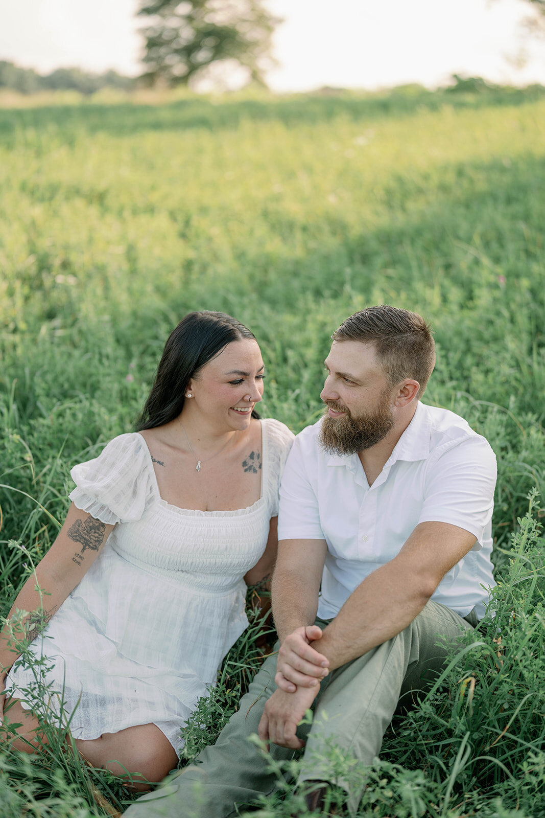Kali and Joe sitting together in tall grass during their intimate Detroit engagement session.