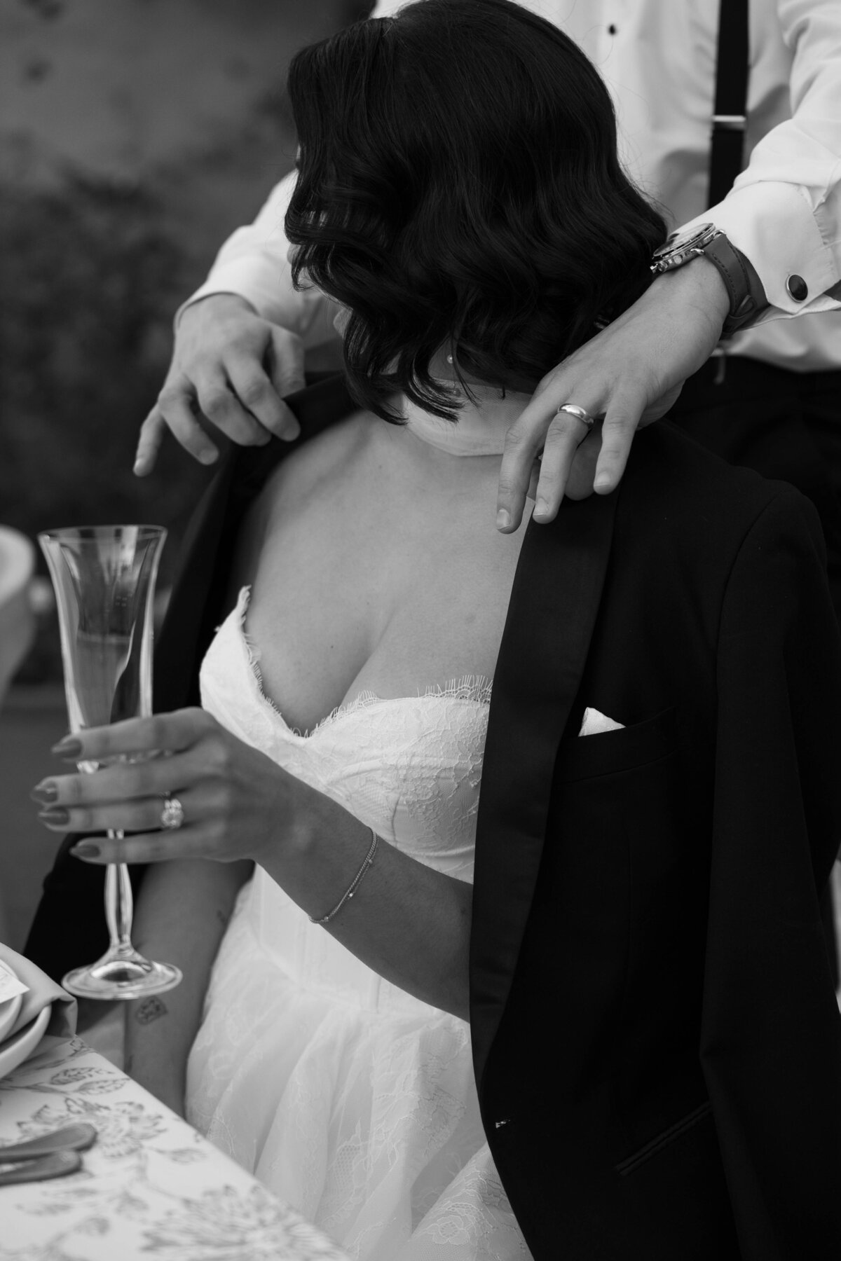 Groom puts suit jacket on his wife during speeches at their Royal Palms wedding reception.