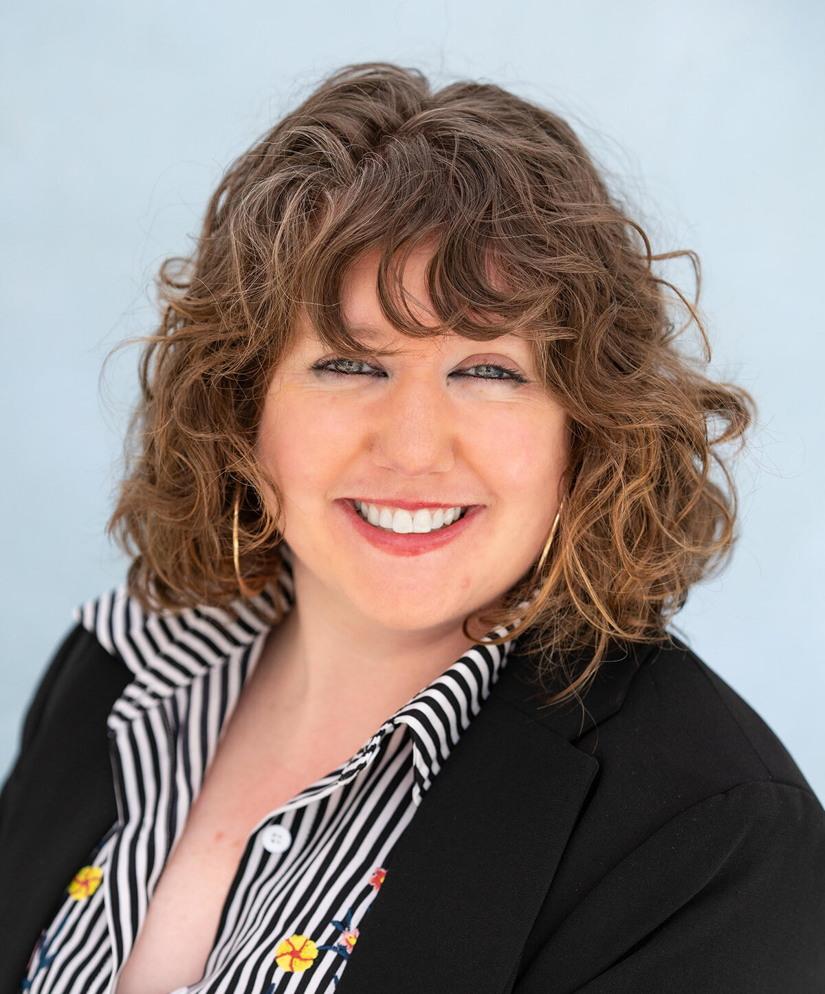 Bright, close-up image of a young woman with curly hair smiling 