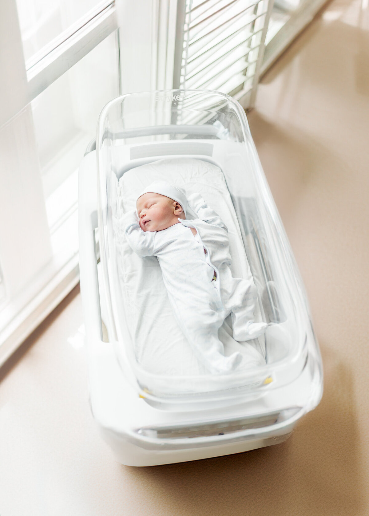 Baby boy laying in crib with eyes closed at Brookwood Hospital during fresh-48 session with 5U Photography