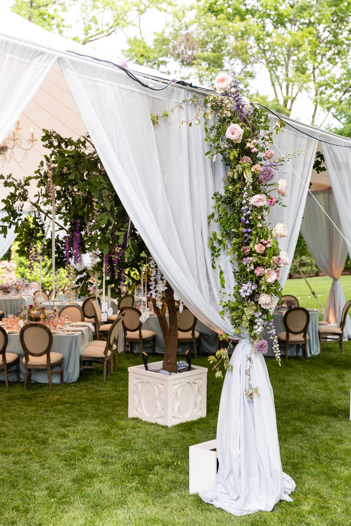 Tent entrance floral installation with blush garden roses, lavender delphinium, globe allium, and vines and greenery for a tented Bridgerton inspired engagement party at a private home in Nashville, TN. Flower by Tennessee based wedding floral design
