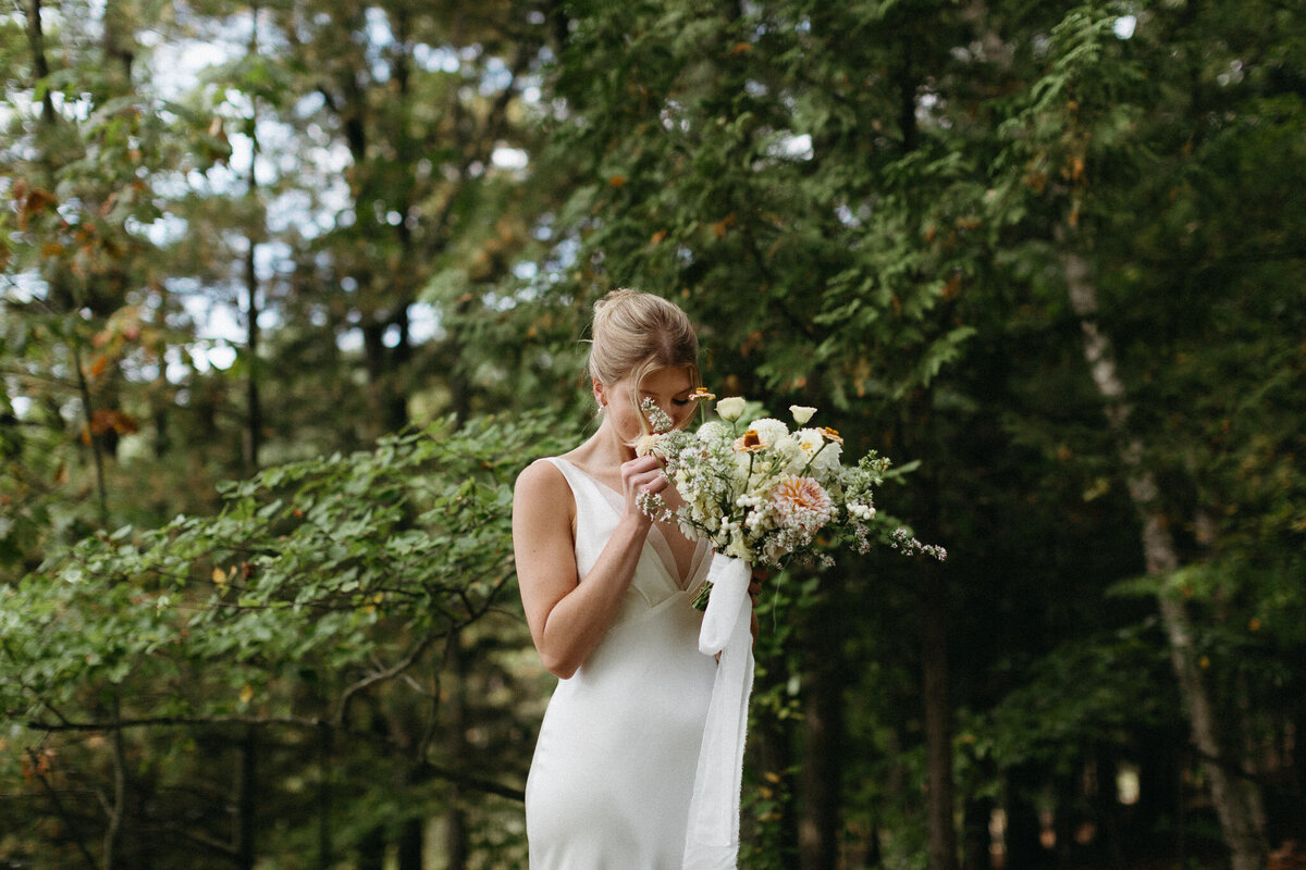 A bride and groom walk up steps toward a brick building with wooden double doors. The bride wears a long white dress, and the groom is in a black suit, their moment beautifully captured by a talented Toronto photographer.