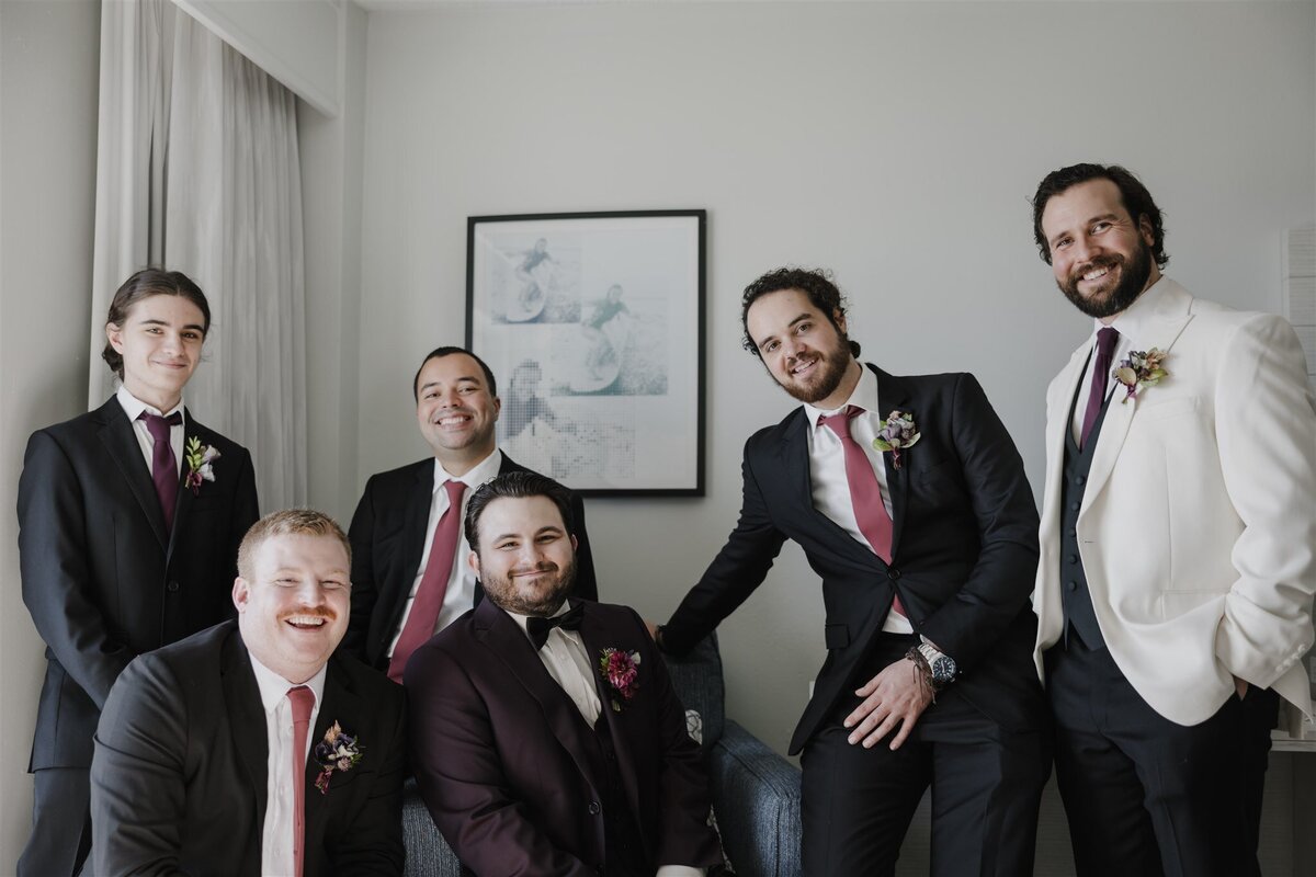 Groom in purple suit with his groomsmen in black suite