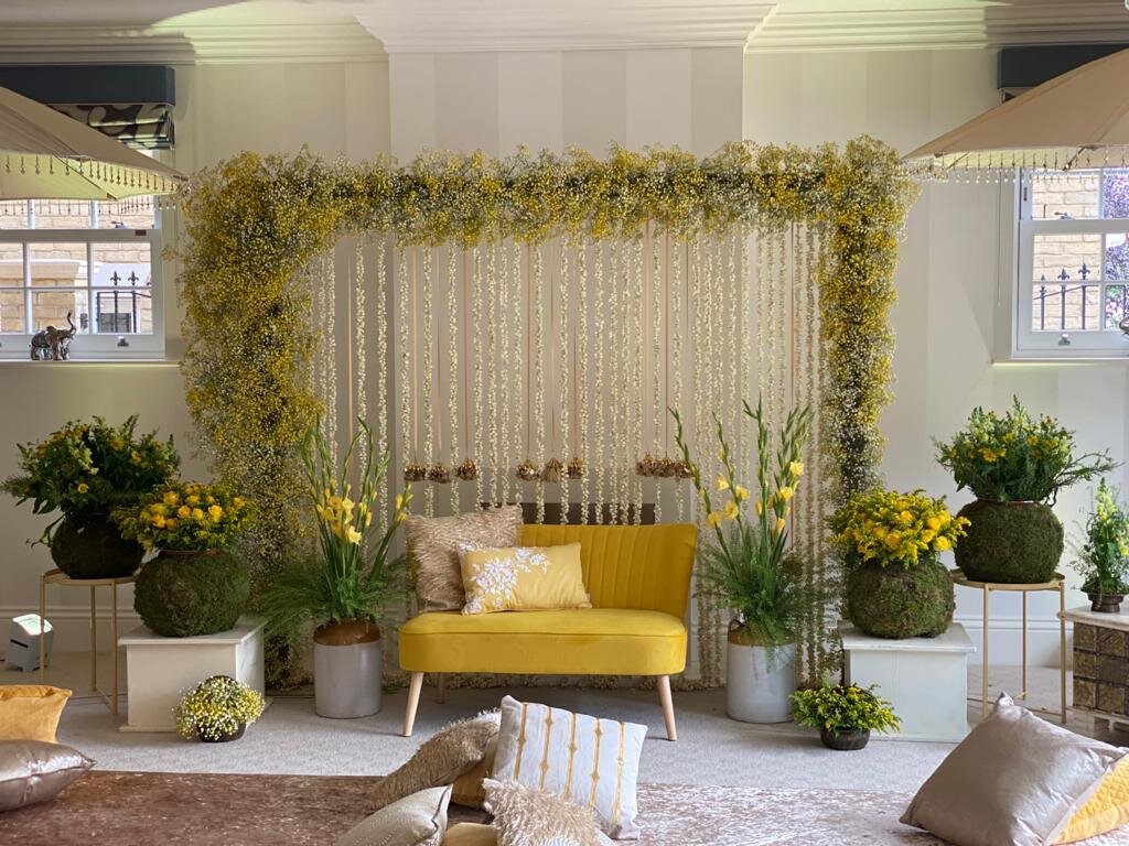 Modern Mehndi event set up with backdrop and sofa