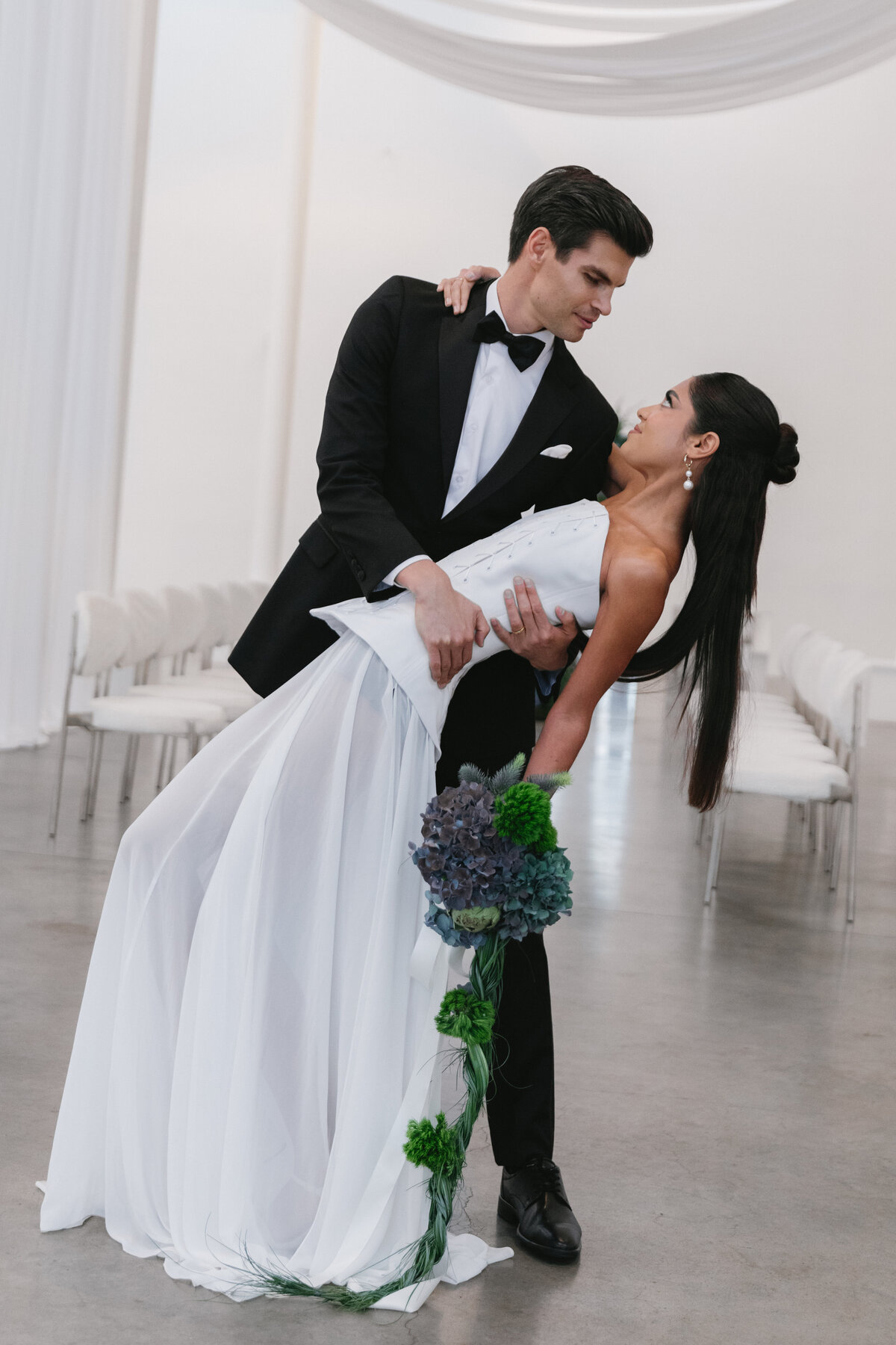 Bride and groom seated together at a modern wedding table adorned with blue and green florals in NYC.
