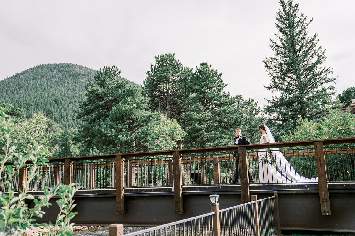 Bride and groom walk across the bride at the Landing in Estes Park.