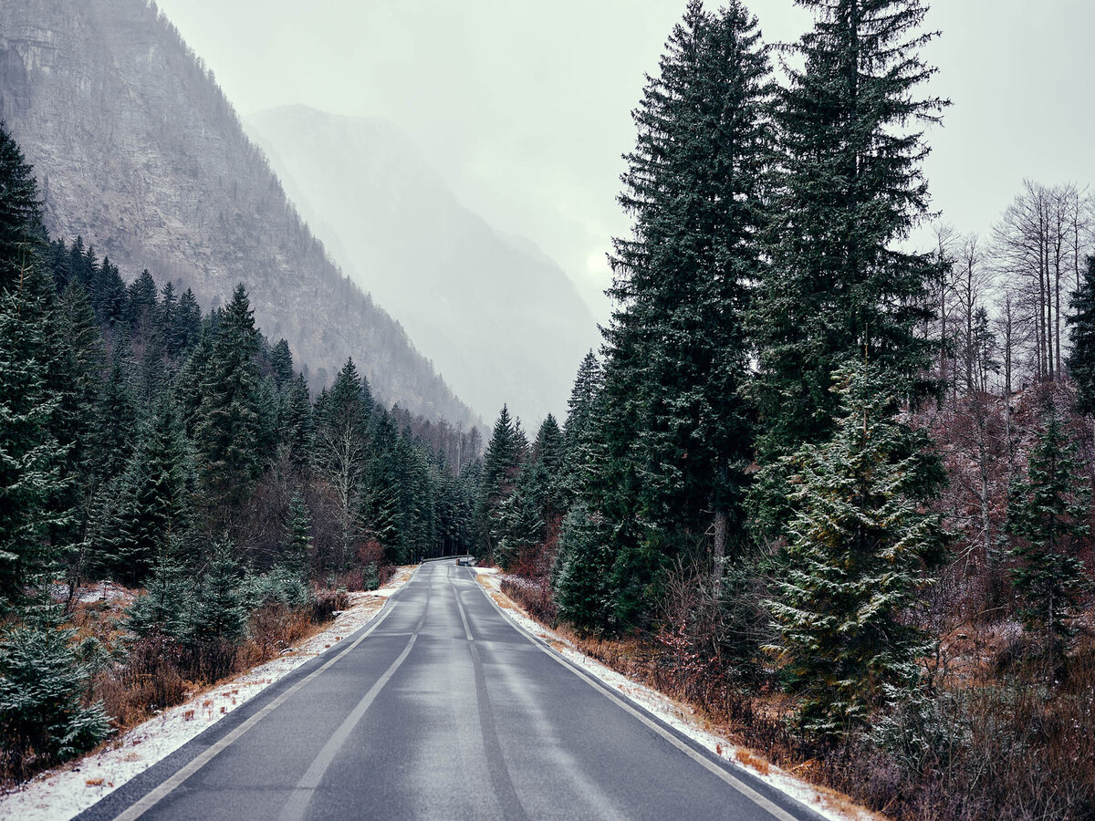 Stimmungsvolle Aufnahme einer verschneiten Bergstraße in Kärnten, flankiert von dichten Nadelwäldern – festgehalten vom Fotograf Atelier Schulte. Spezialist für Alpenlandschaften und professionelle Landschaftsfotografie in ganz Österreich mit Fokus auf besondere Lichtstimmungen und Atmosphäre.