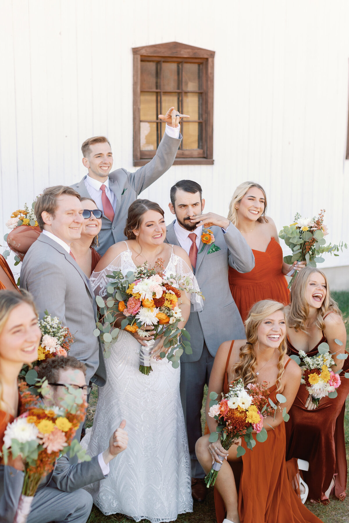 Bride and groom with full wedding party cheering and laughing outside The Hummingbird Chateau.