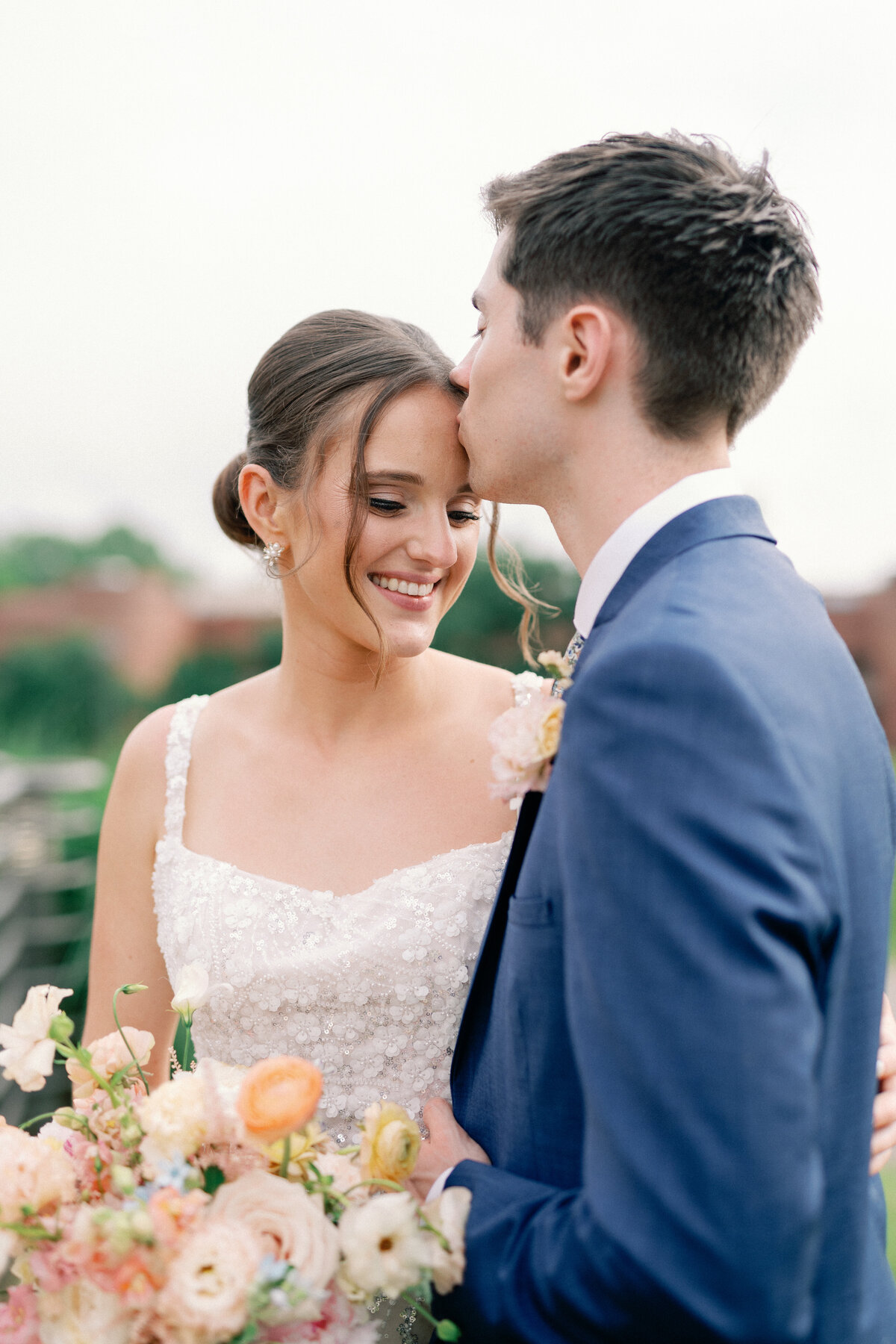 Groom in blue tux kisses bride on forehead by Illinois wedding photographer Lacey Graham 