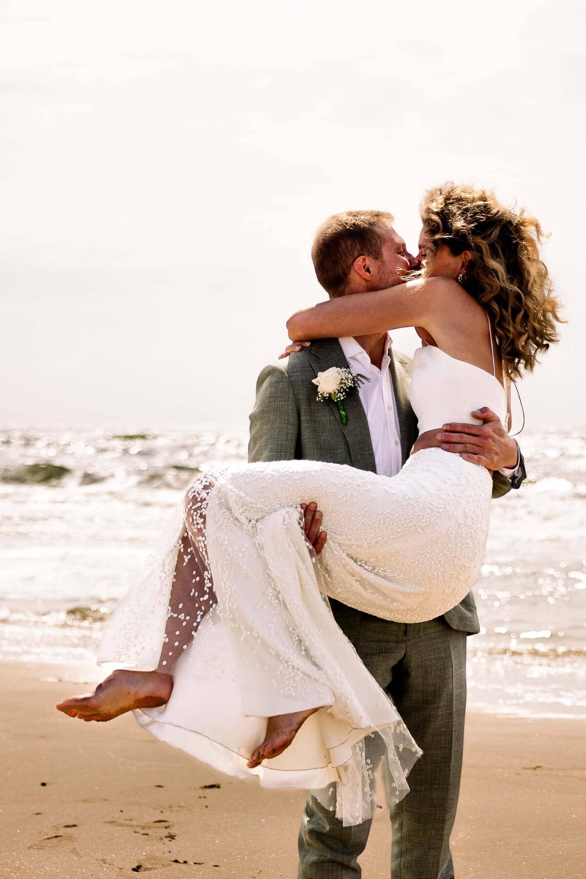 Huwelijksfoto dansend samen op het strand-min