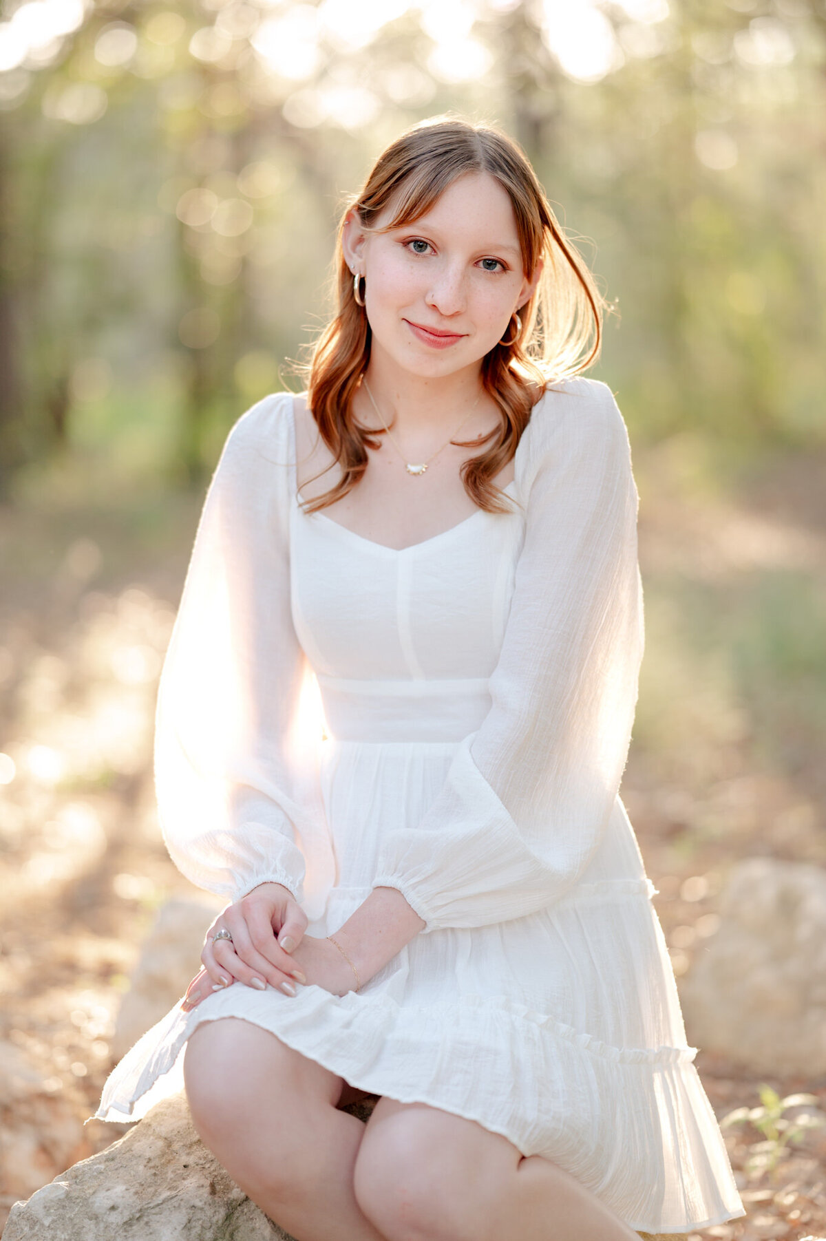 Senior picture of a redhead in a white dress and glowing backlight.