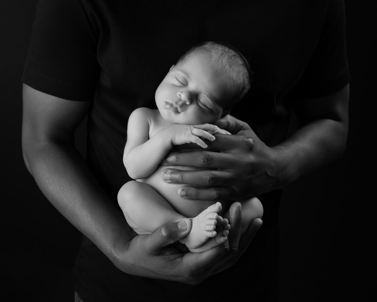 Black white parent hands holding newborn Cedar Park artistic lifestyle photographer