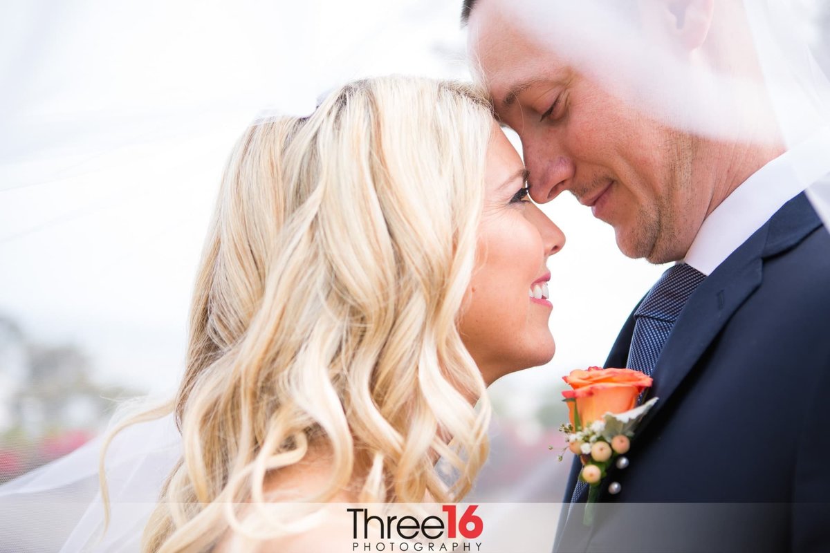 Sweet moment under the Bride's veil for newly married couple