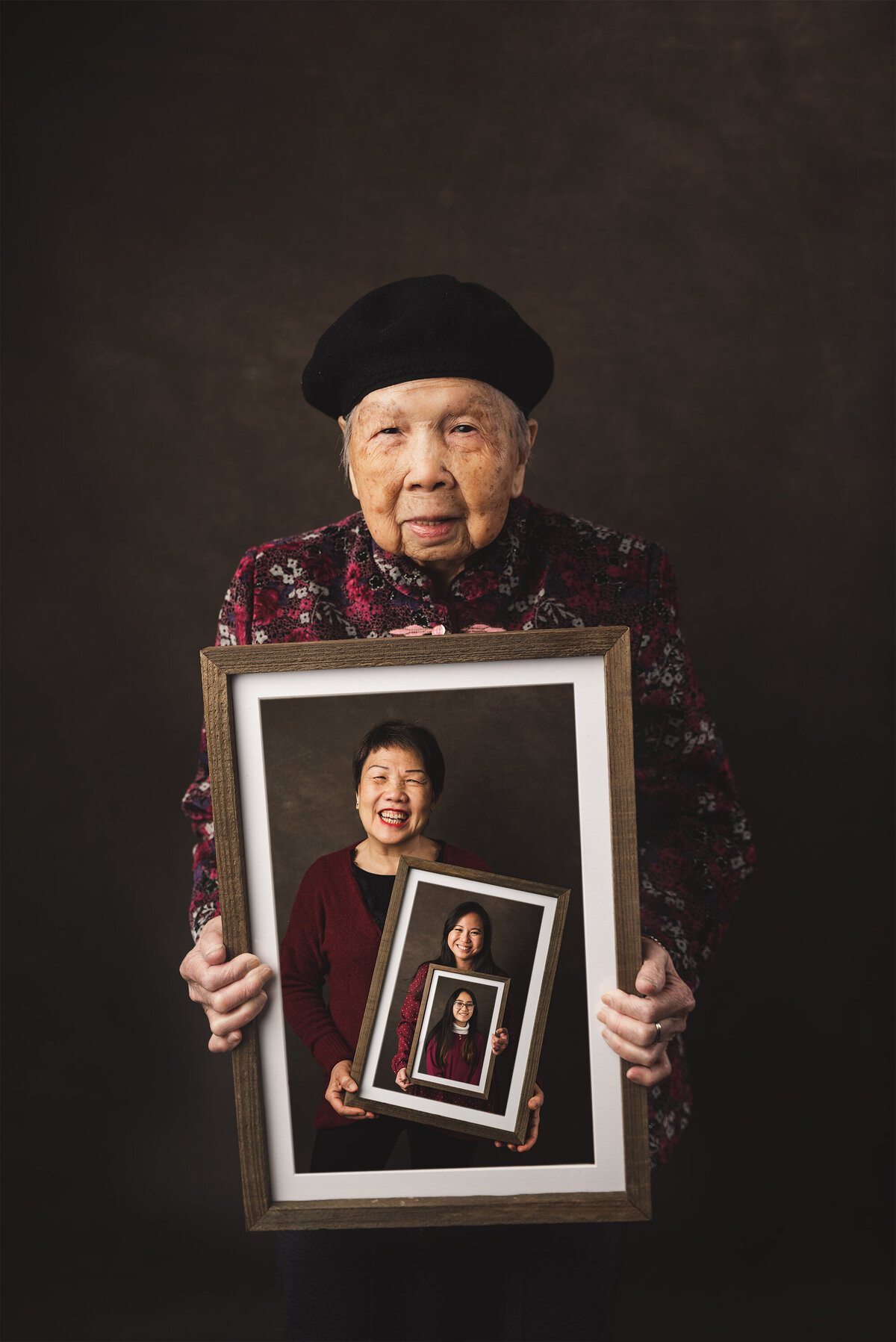 Studio portrait of grandmother holding photos of daughter, granddaughter, and great-granddaughter — timeless generational photography in Sausalito