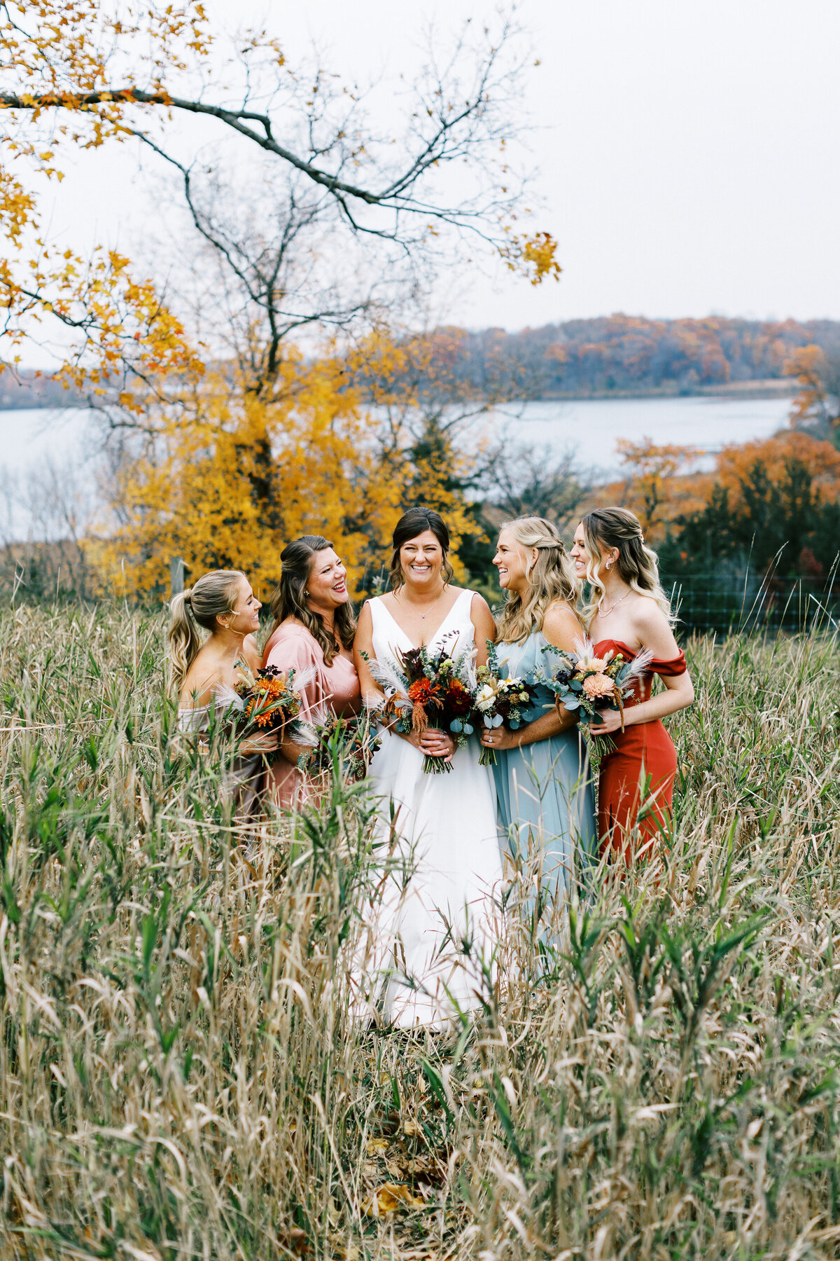 bride is surrounded by her bridesmaids with smiles looking at her