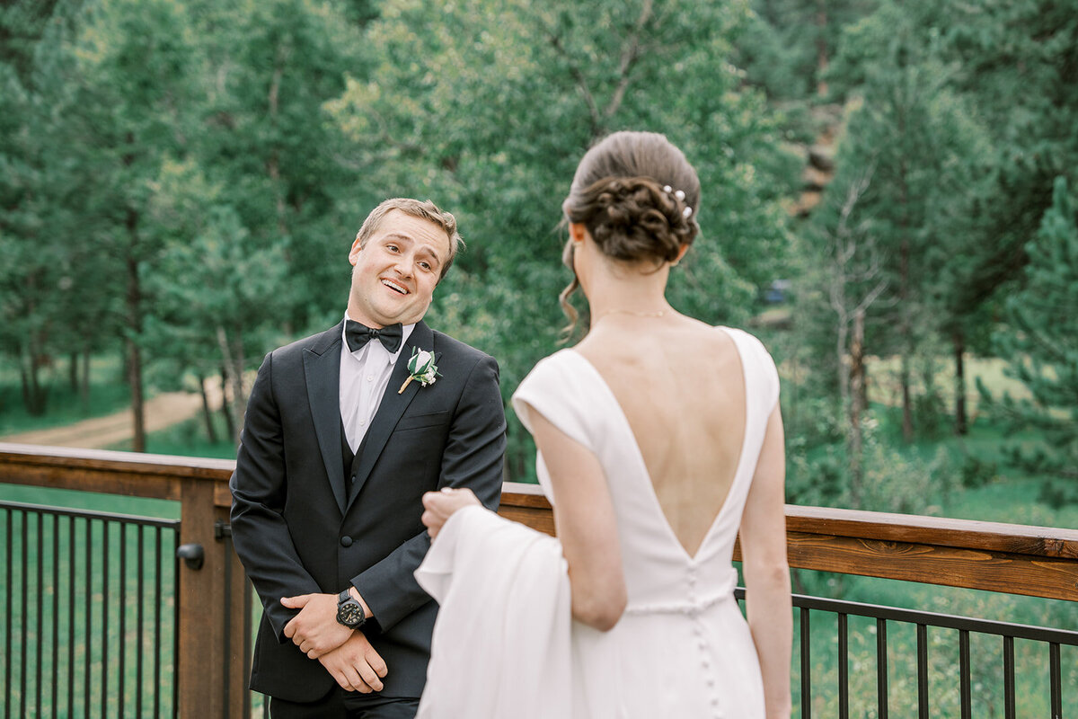 Groom smiles as he sees his lovely bride for the first time on their wedding day at the Landing in Estes Park.