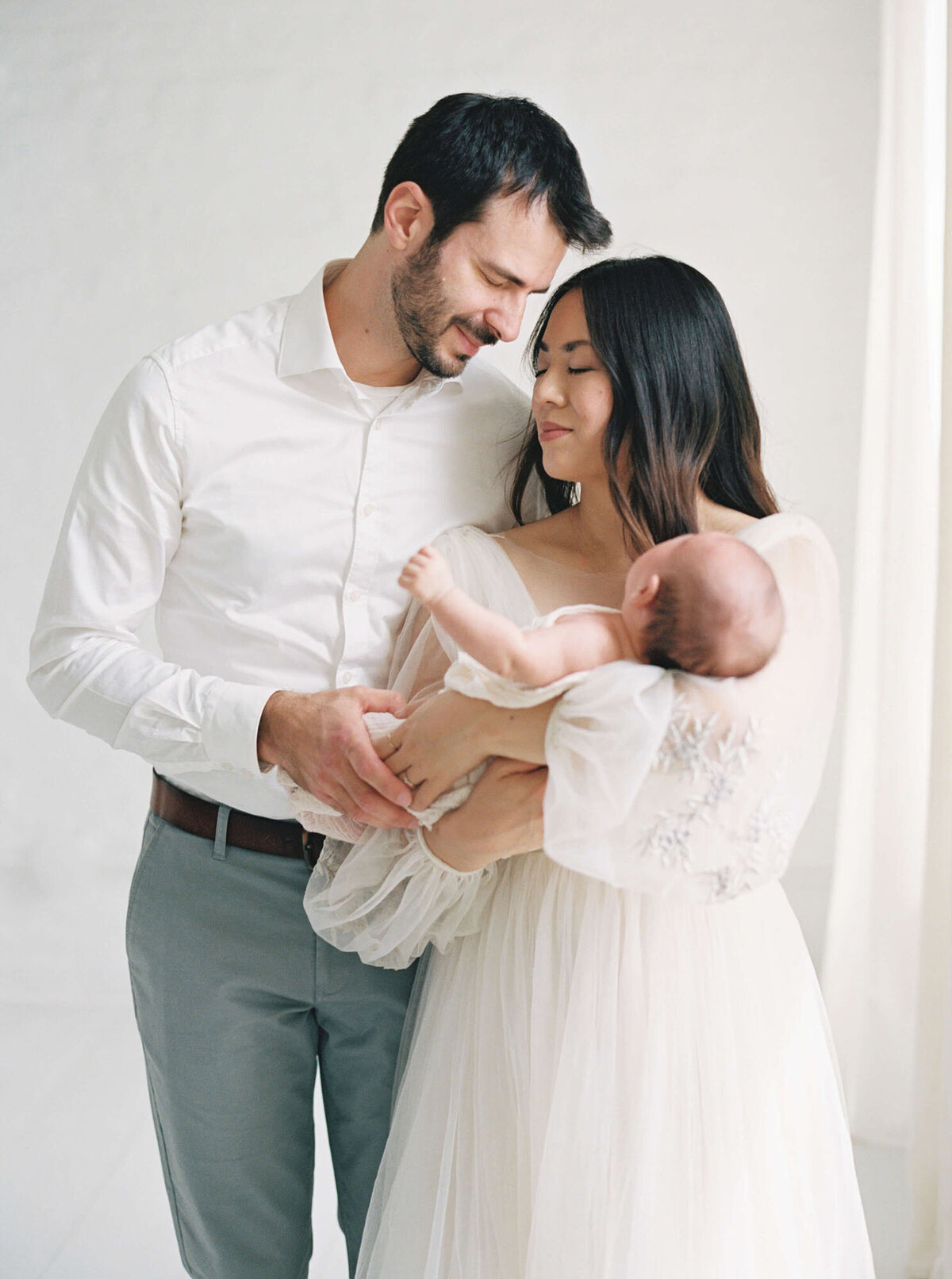 Parents cuddling their newborn during an in-home San Francisco Bay Area newborn photographer session.