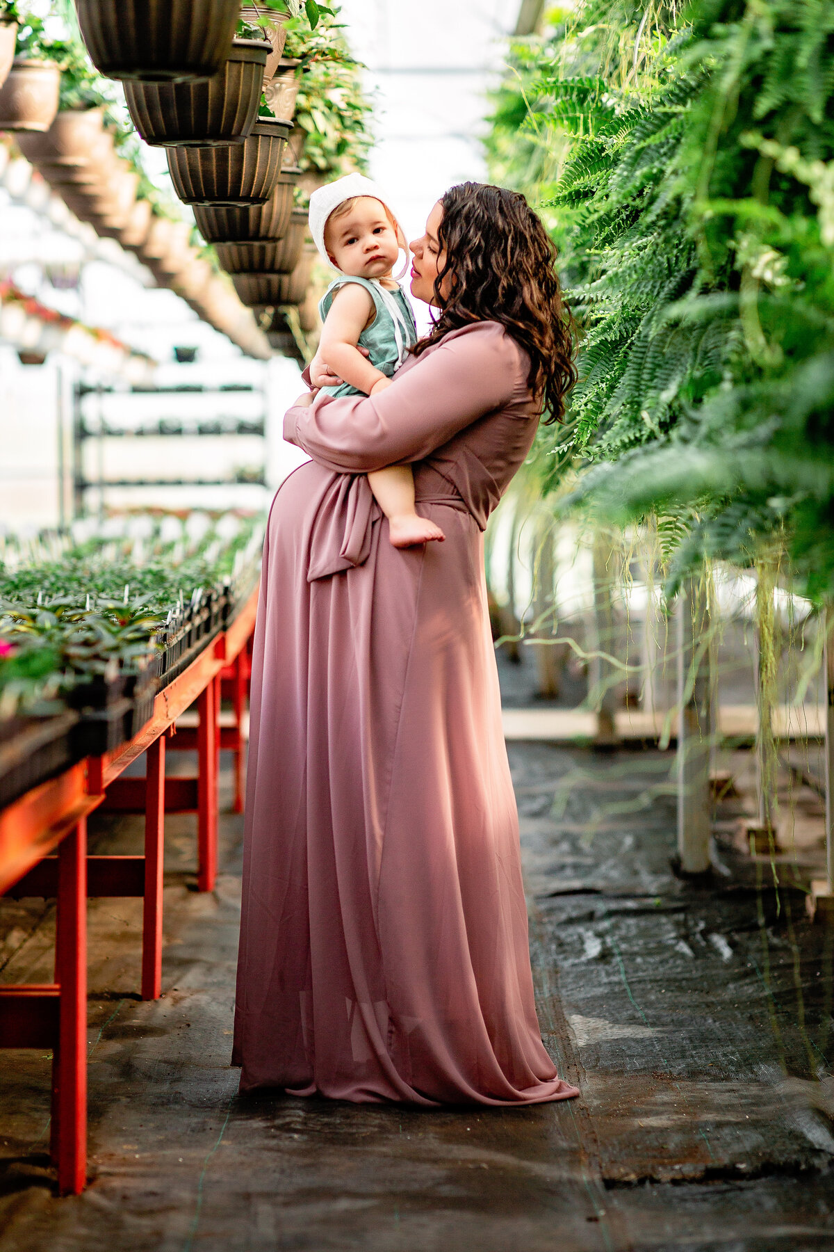 Mom in mauve dress with son at a greenhouse