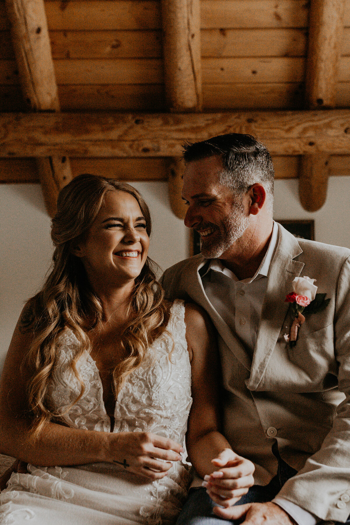 bride and groom sitting together laughing inside of a cabin