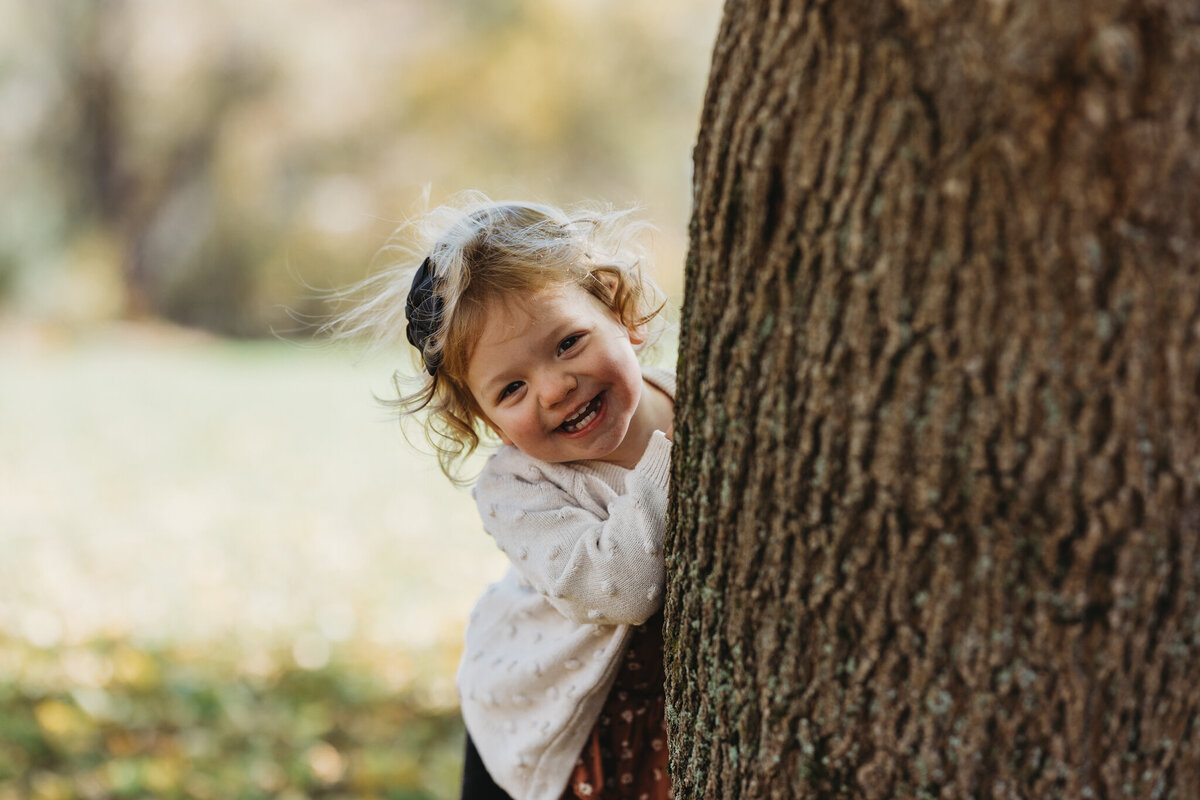 little girl behind tree