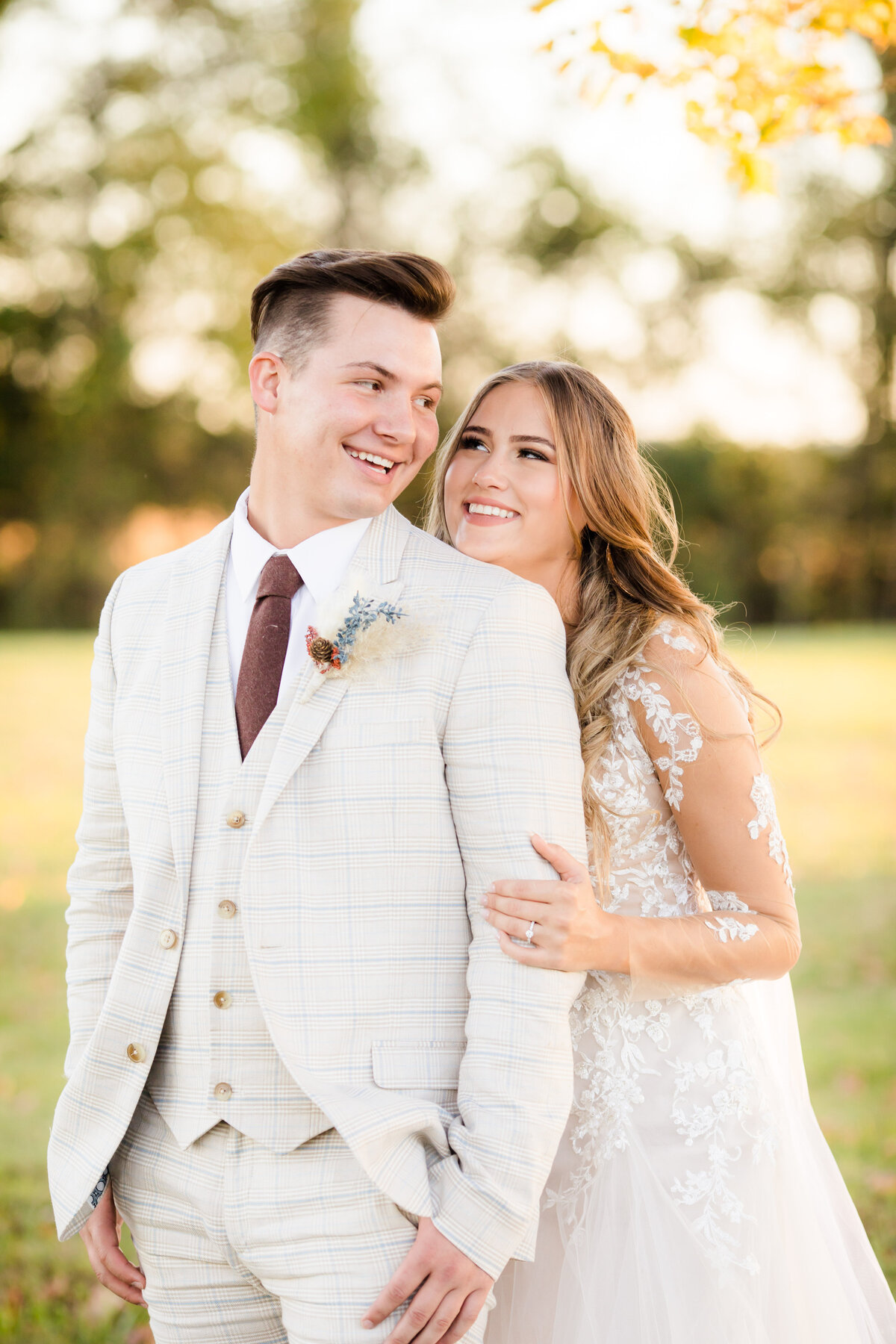 Bide hugging behind groom with him looking over his shoulder both smiling at each other