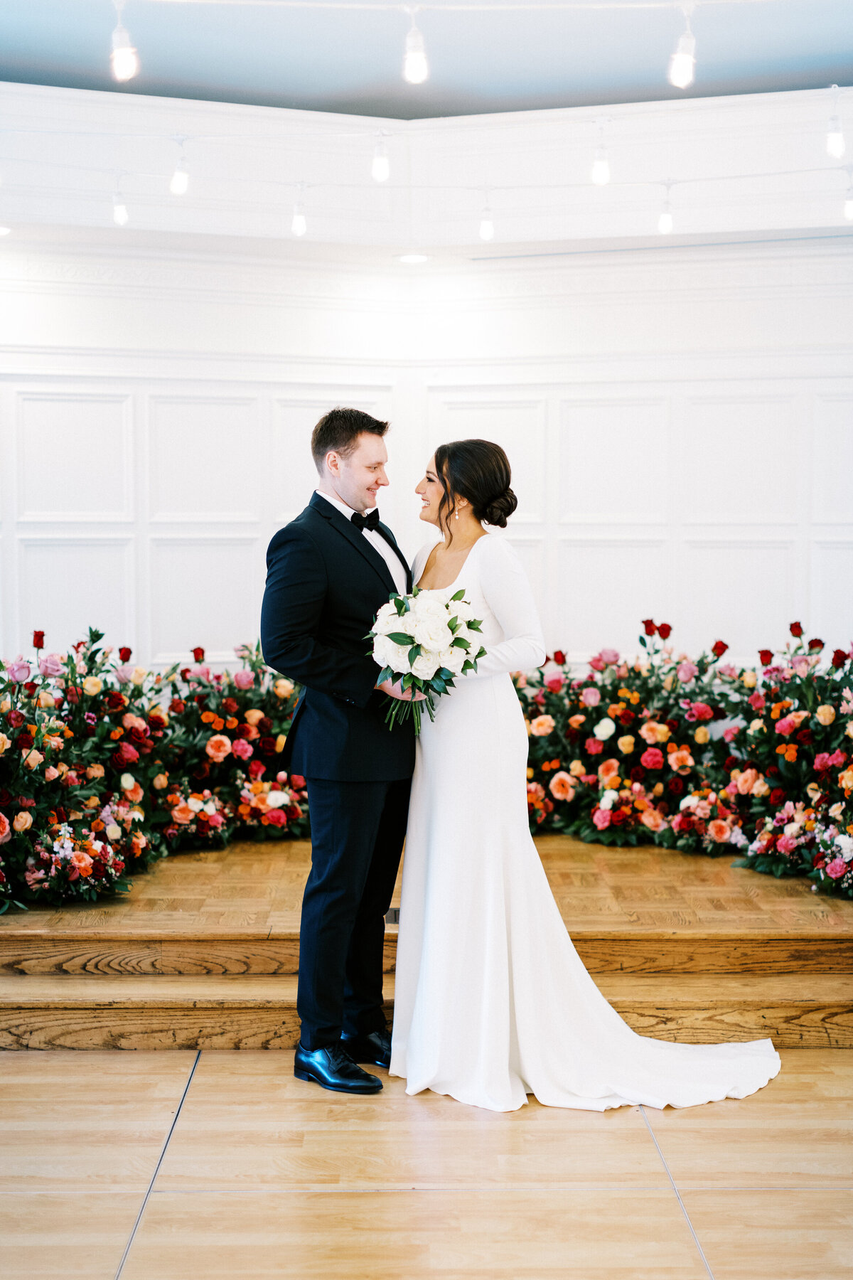 Bride and groom looking at each others eyes surrounded by beautiful flowers