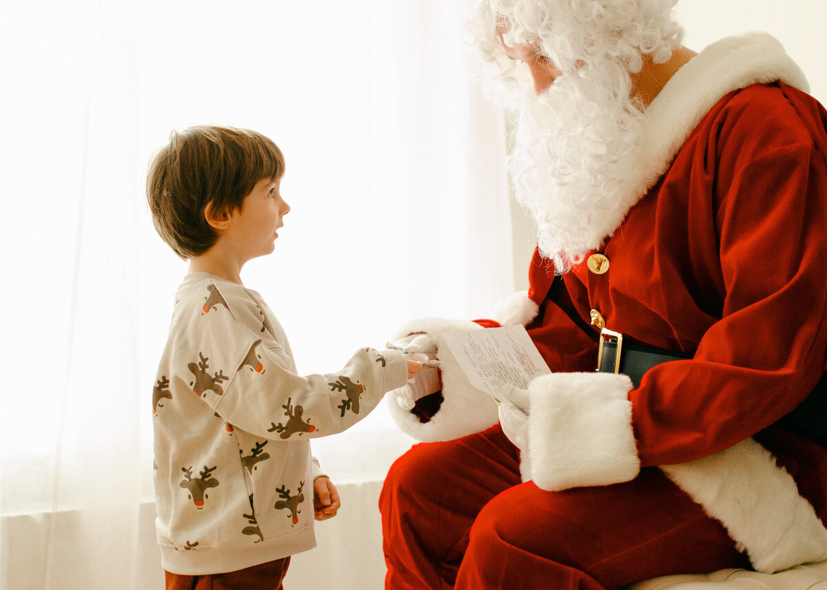 Child gives Santa his Christmas letter in a photostudio in Amsterdam West.