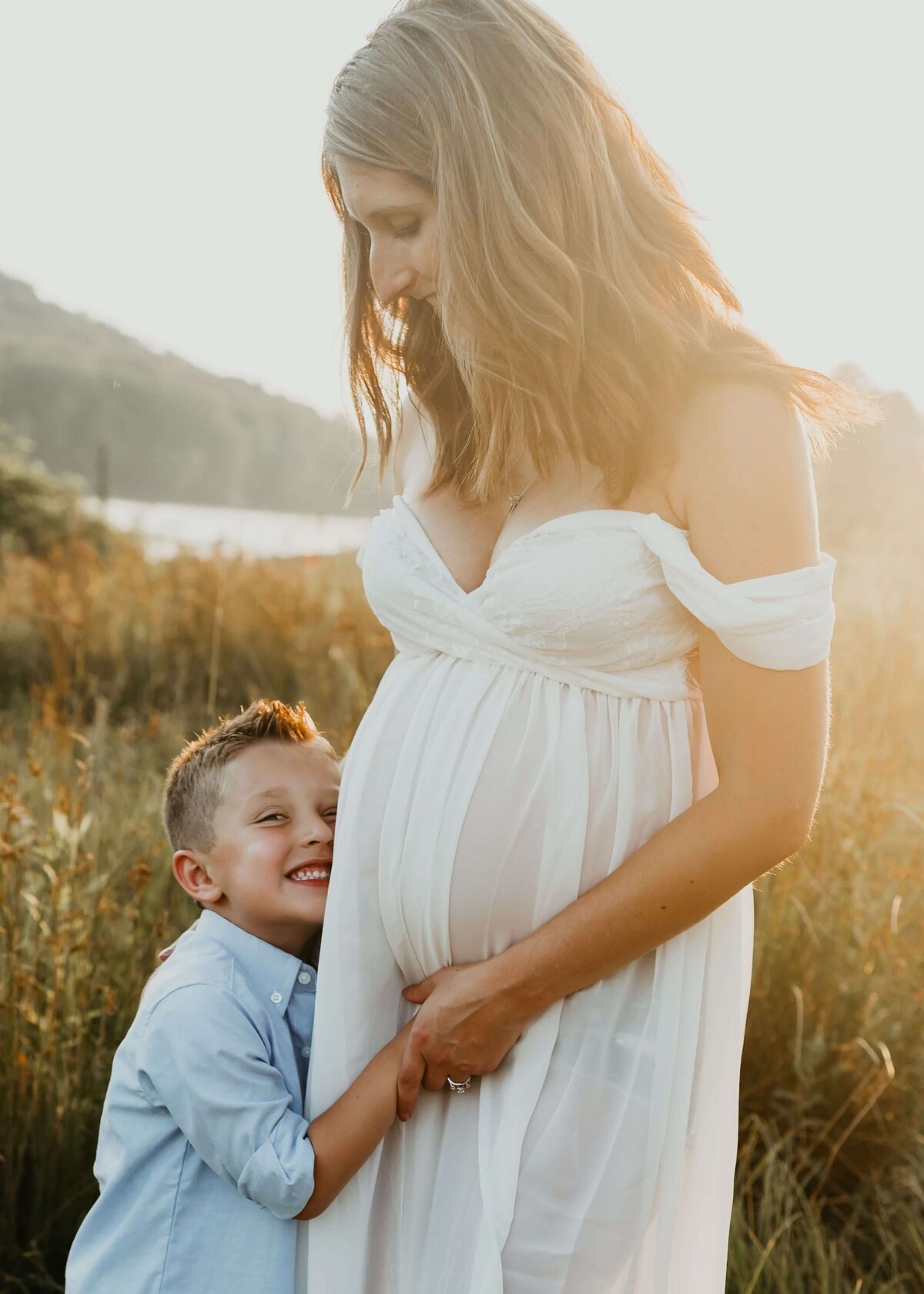 A pregnant woman and her son in a field at sunset captured by a Pittsburgh maternity photographer.
