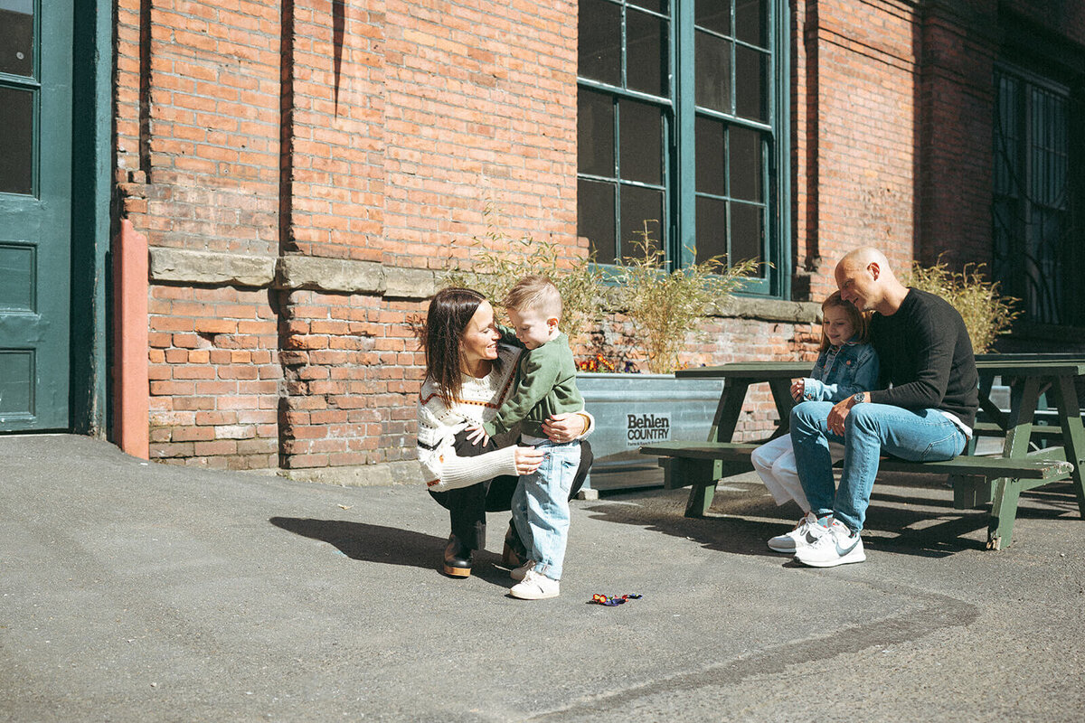 Natural family moment captured in a city courtyard with parents and kids interacting during lifestyle session