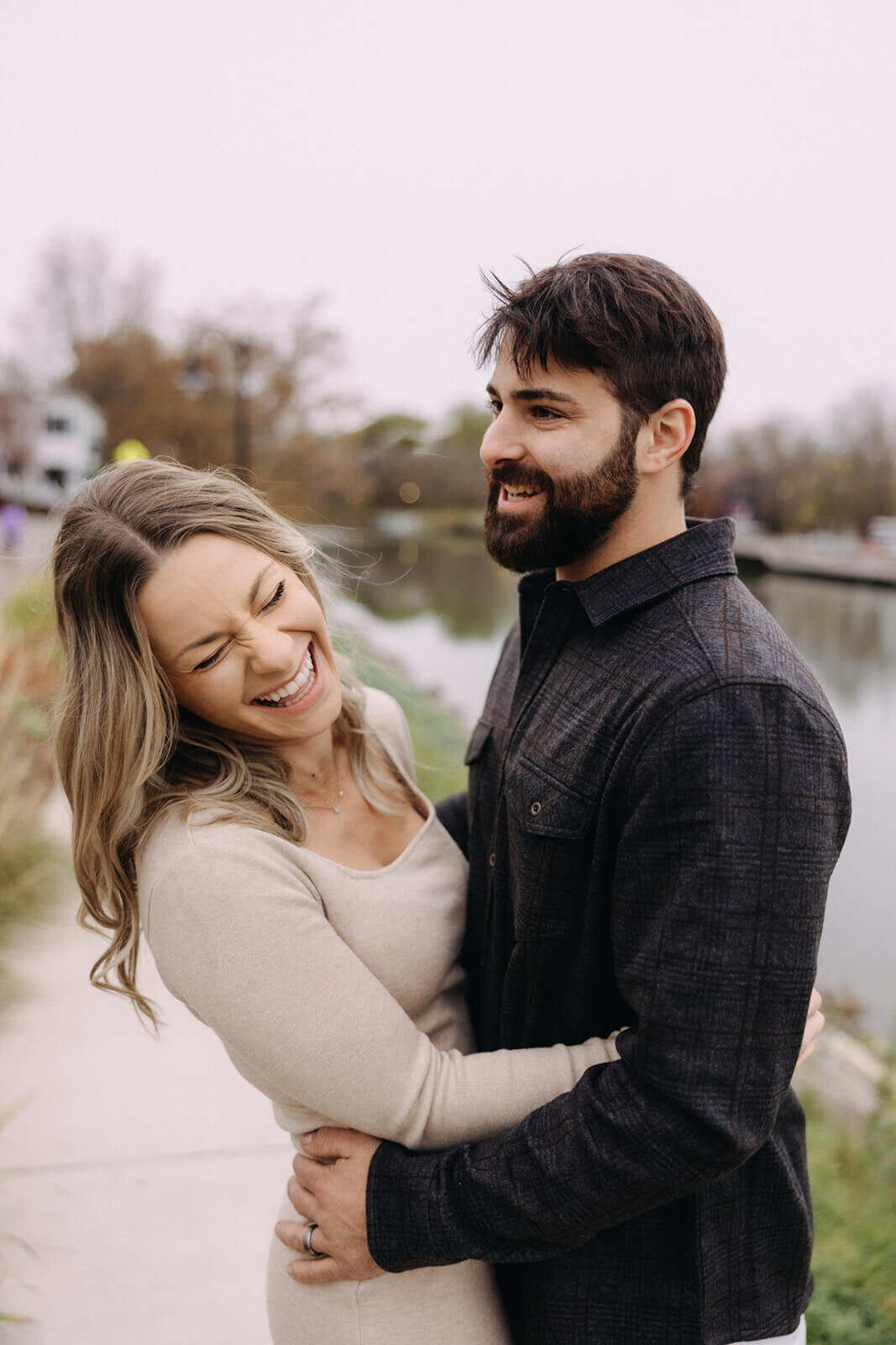 Man and woman laughing and hugging at at Finger Lakes maternity session