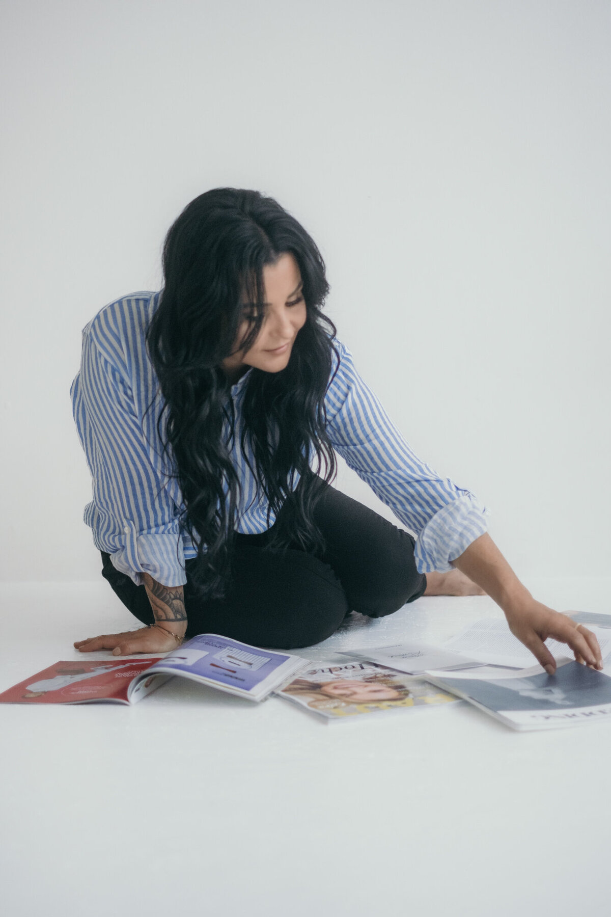 Woman sits on the floor, looking at pictures and magazines.