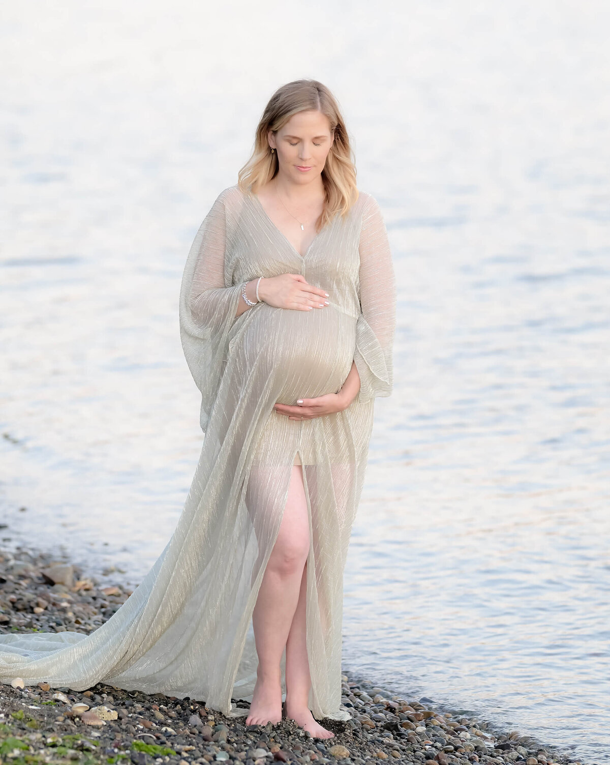 Light and airy maternity session on a rocky PNW beach. The mom-to-be is beautifully captured in a serene coastal setting. Image by E. Benecki Photography.