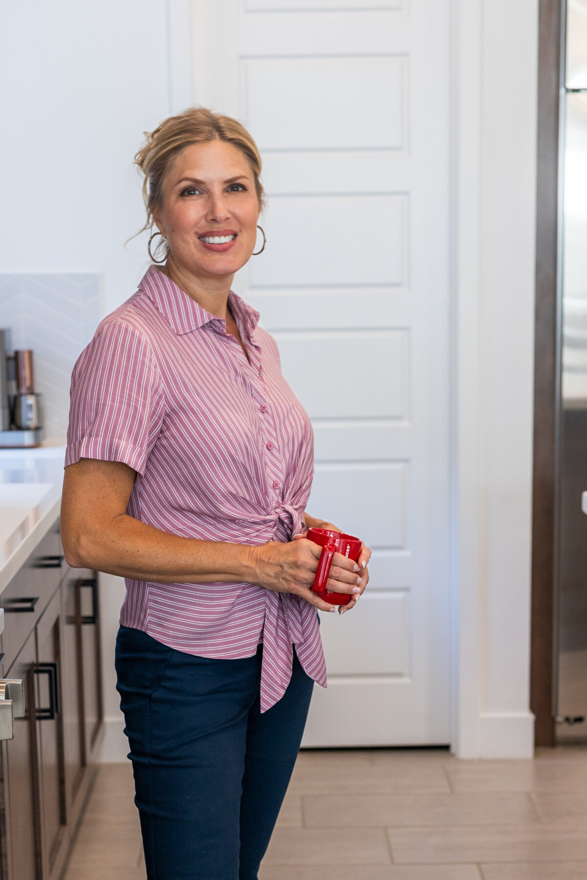 Laura Bogart at home in her kitchen with a red mug in hand