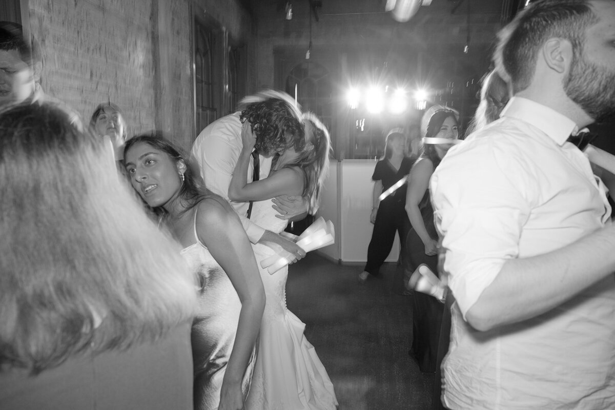 Cinematic kiss dip moment during late-night wedding reception with flash and red uplighting