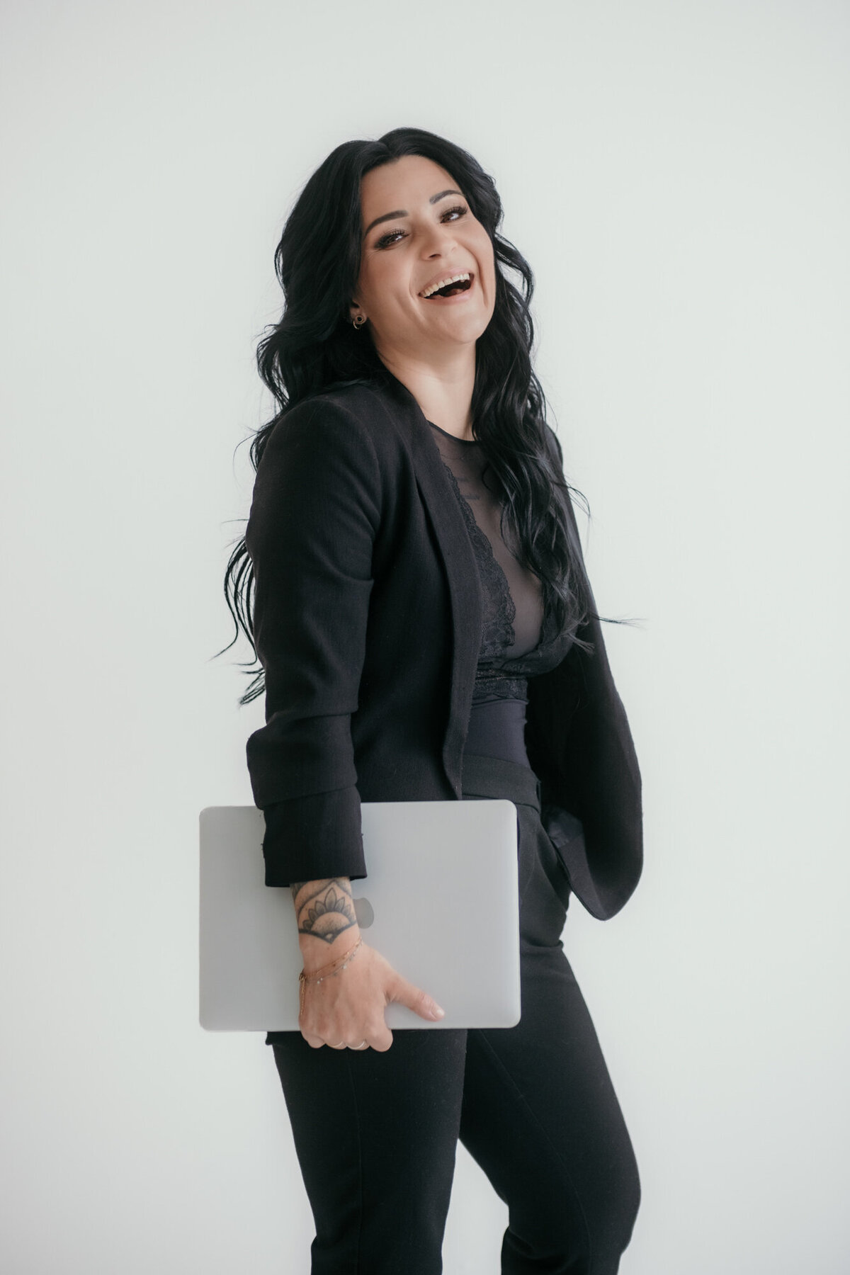 Confident businesswoman smiling at the camera, holding a laptop — portrait photography for professionals