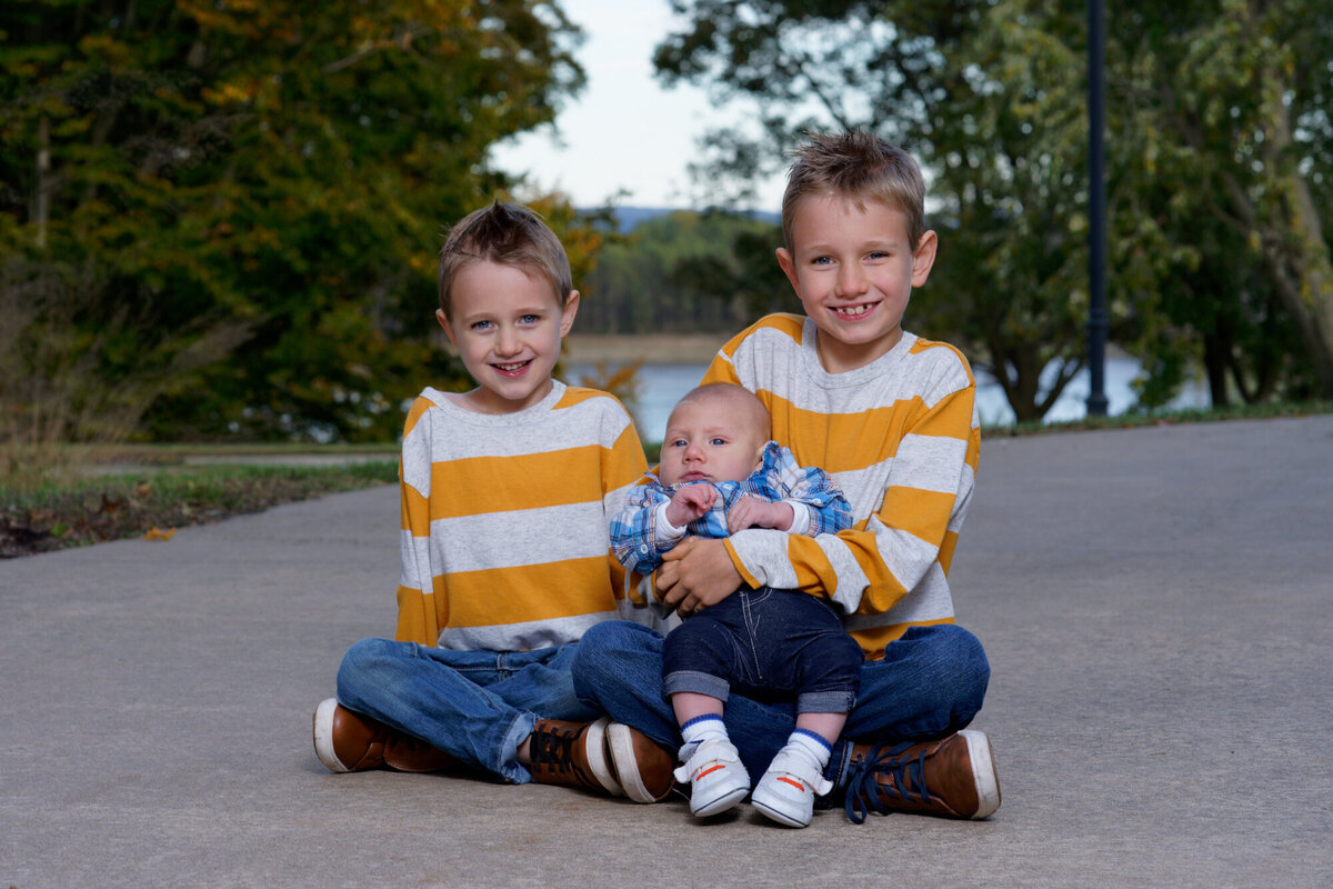 two brothers and baby sister sitting on sidewalk portrait