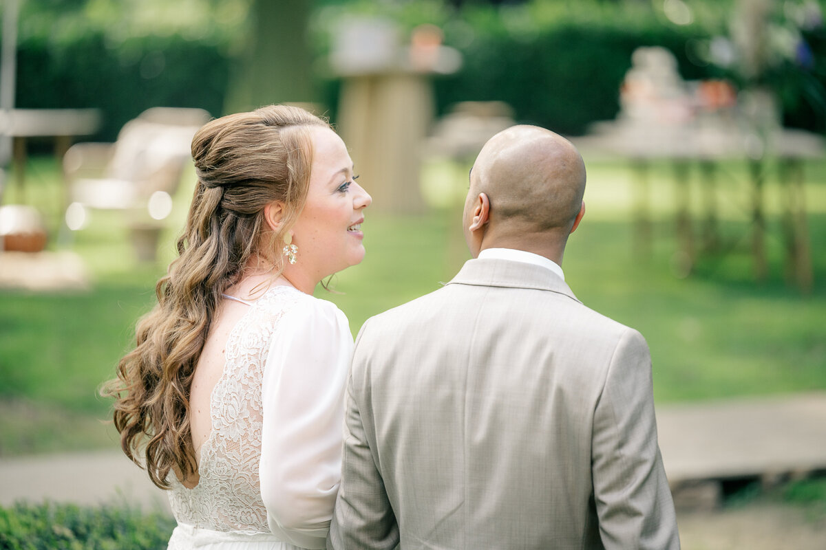 A bride and groom talk to each other as they walk away in their recessional after their garden wedding ceremony