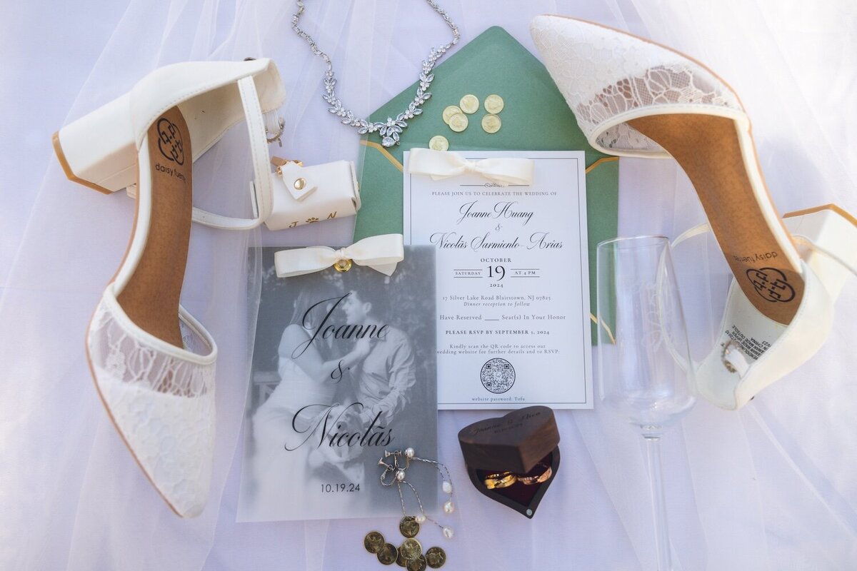 Flatlay of white bridal shoes, wedding invitation suite, jewelry, and veil details at Silver Lake.