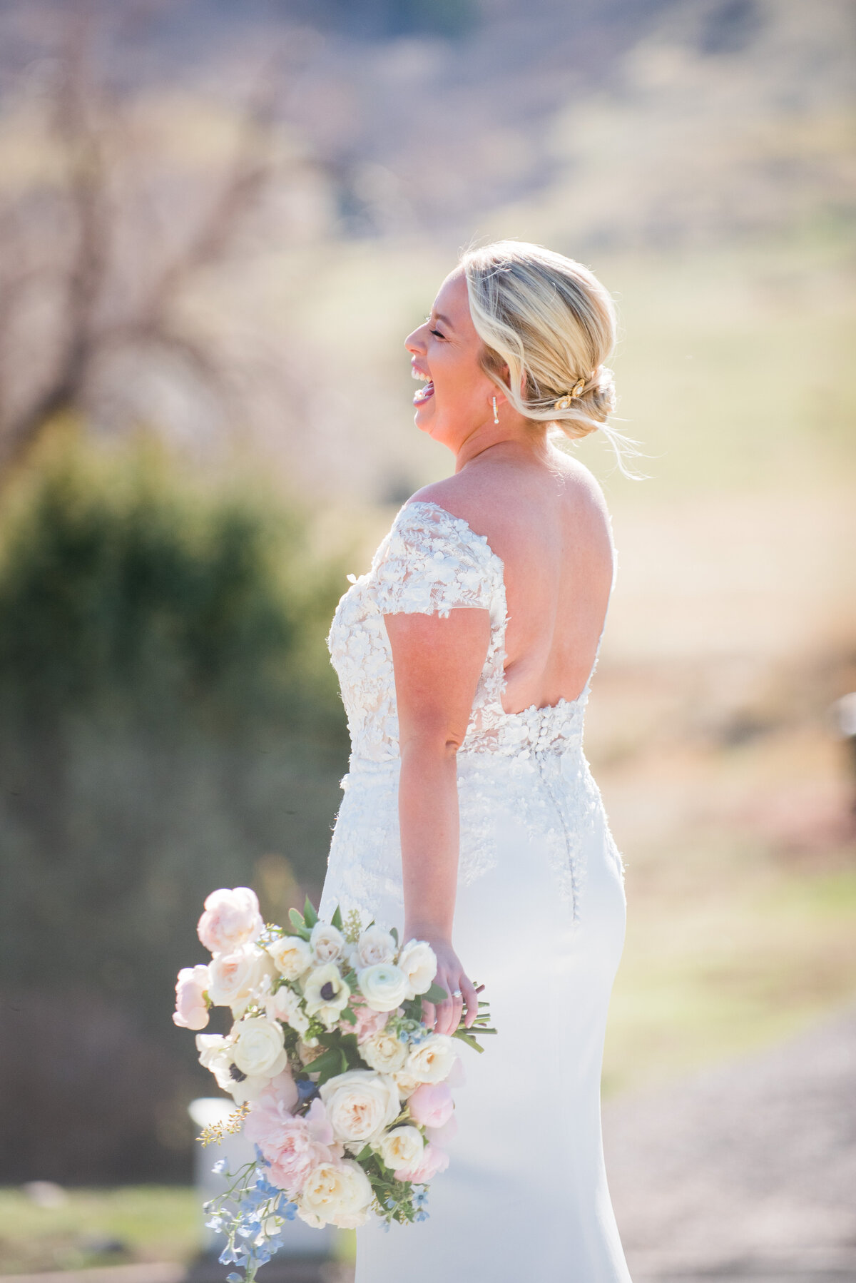 A bride stares off into the distance laughing candidly, captured by Denver wedding photographer, Two One Photography.