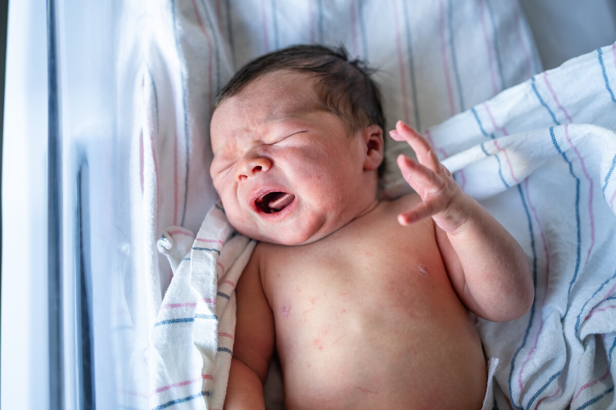 Newborn baby crying in bassinet