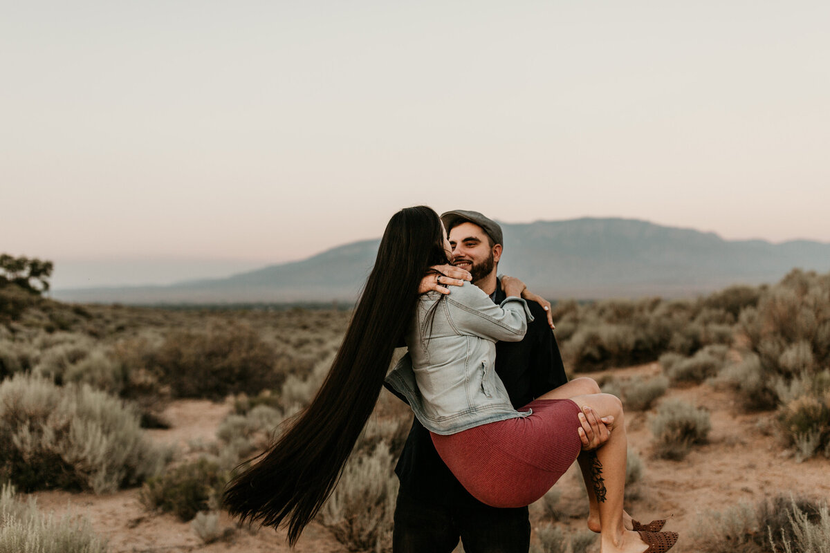 man holding long haired woman in desert