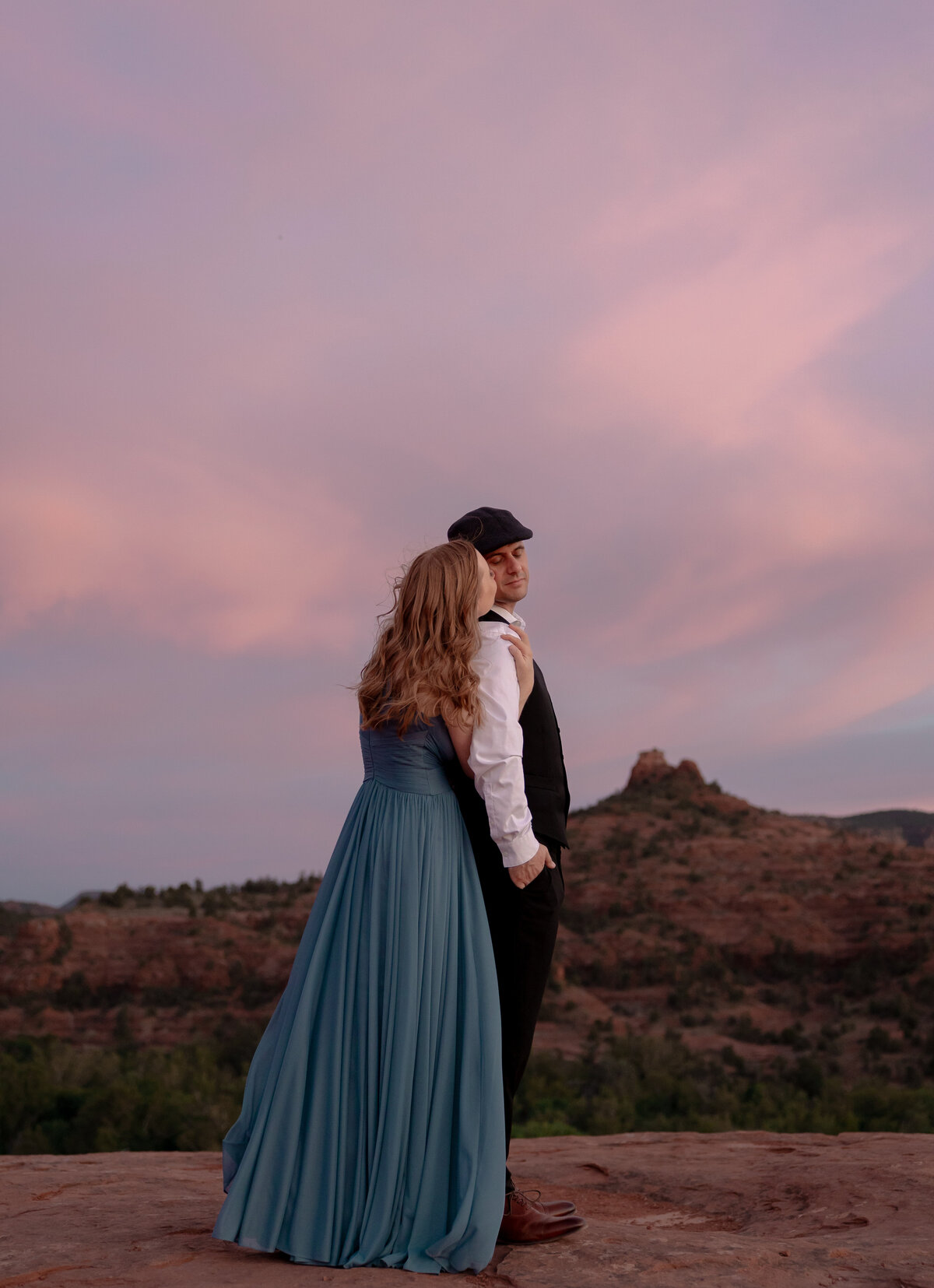 Couple standing against red rock backdrop during Sedona engagement session