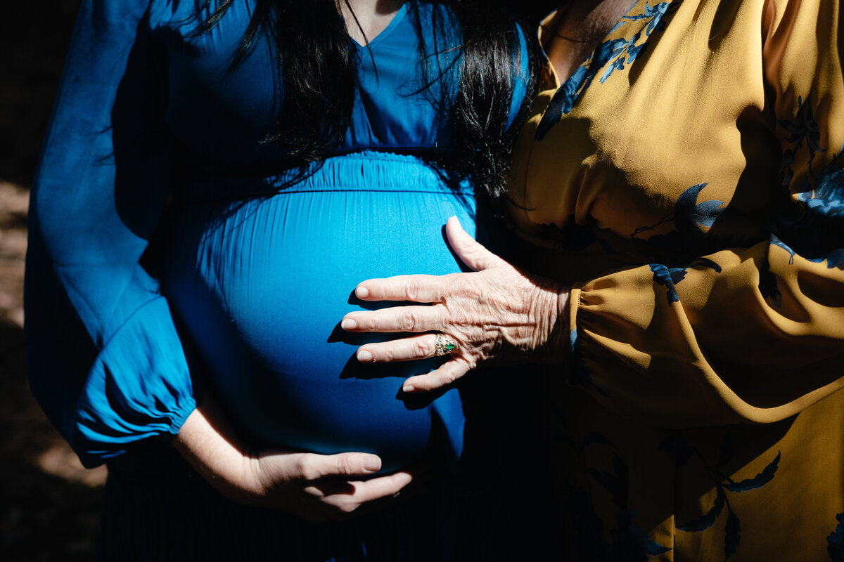 Grandmother's hand is placed on her daughter's pregnant stomach